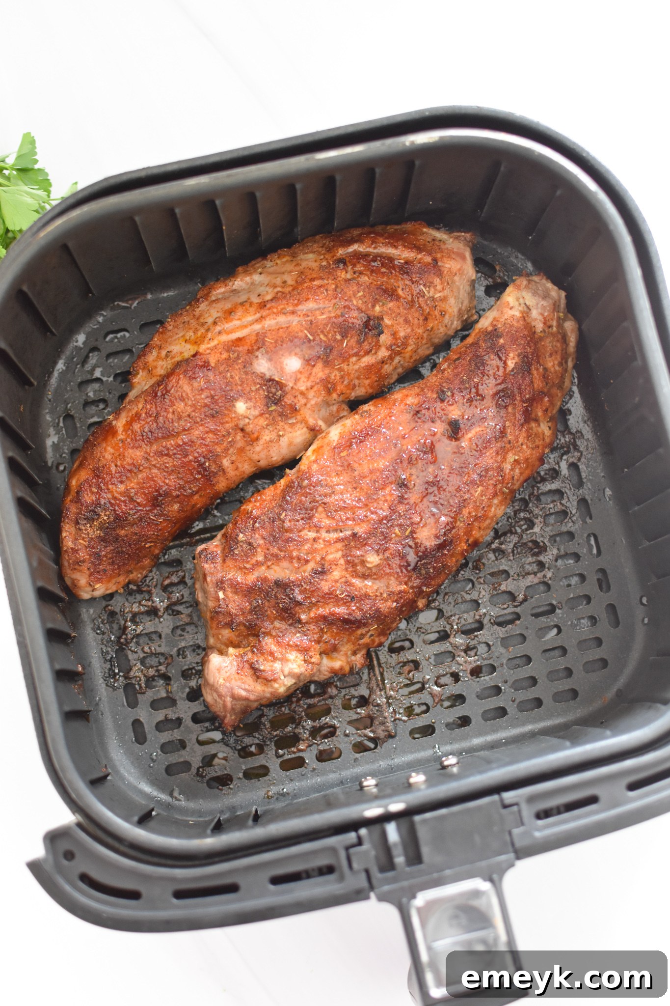 Air Fryer Pork Tenderloin cooking inside the air fryer basket, showing a golden brown, crusted exterior.