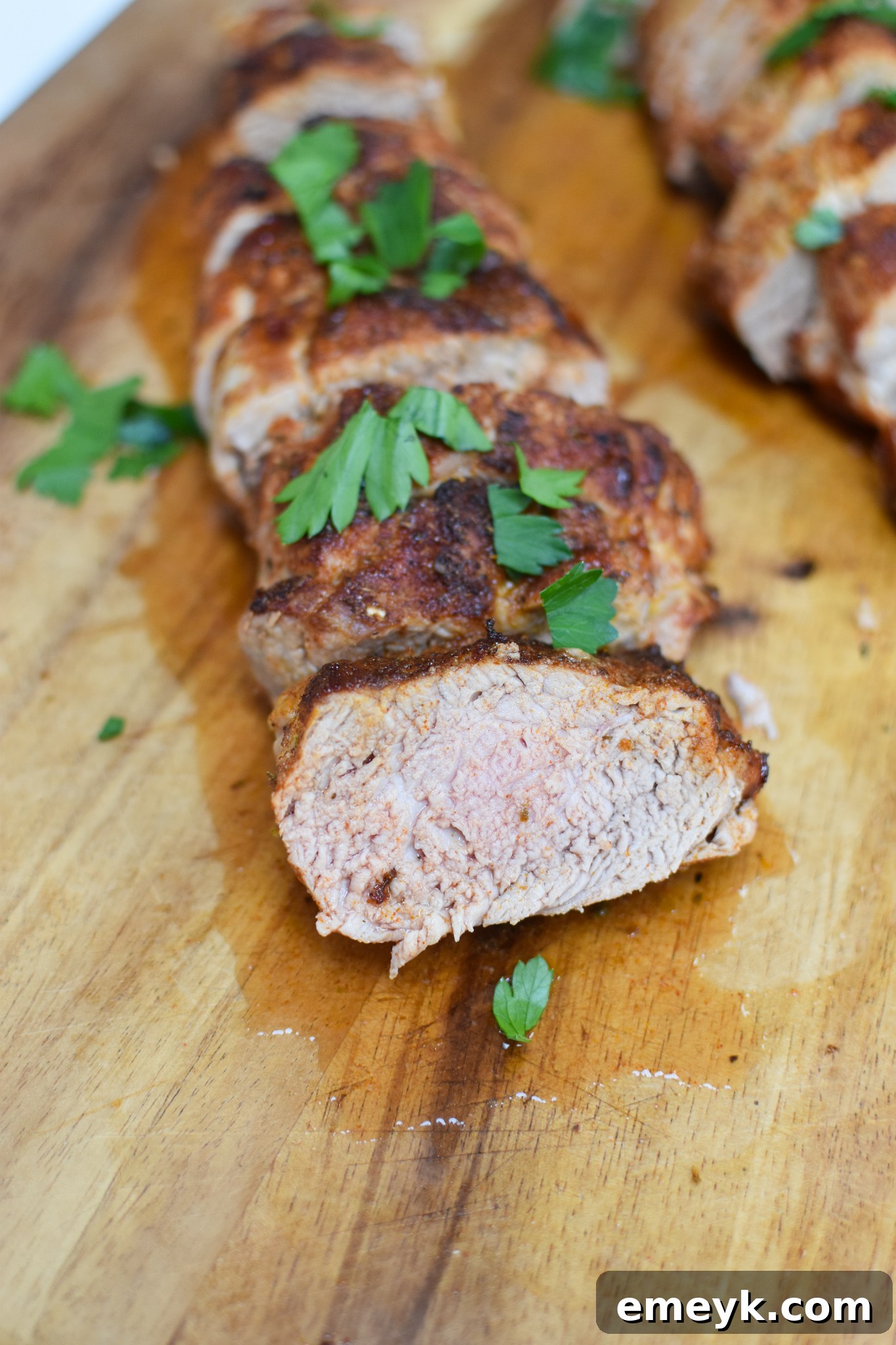 Slices of juicy Air Fryer Pork Tenderloin on a wooden cutting board, ready for serving.