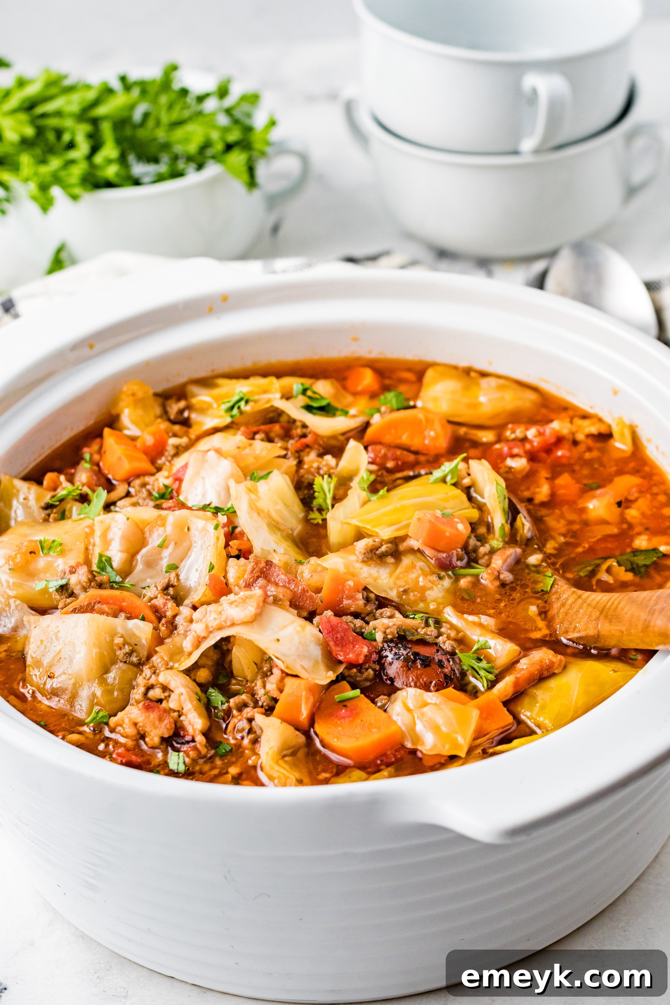 Unrolled Cabbage Soup 8 Cabbage Roll Soup in a white pot with a wooden spoon for serving.