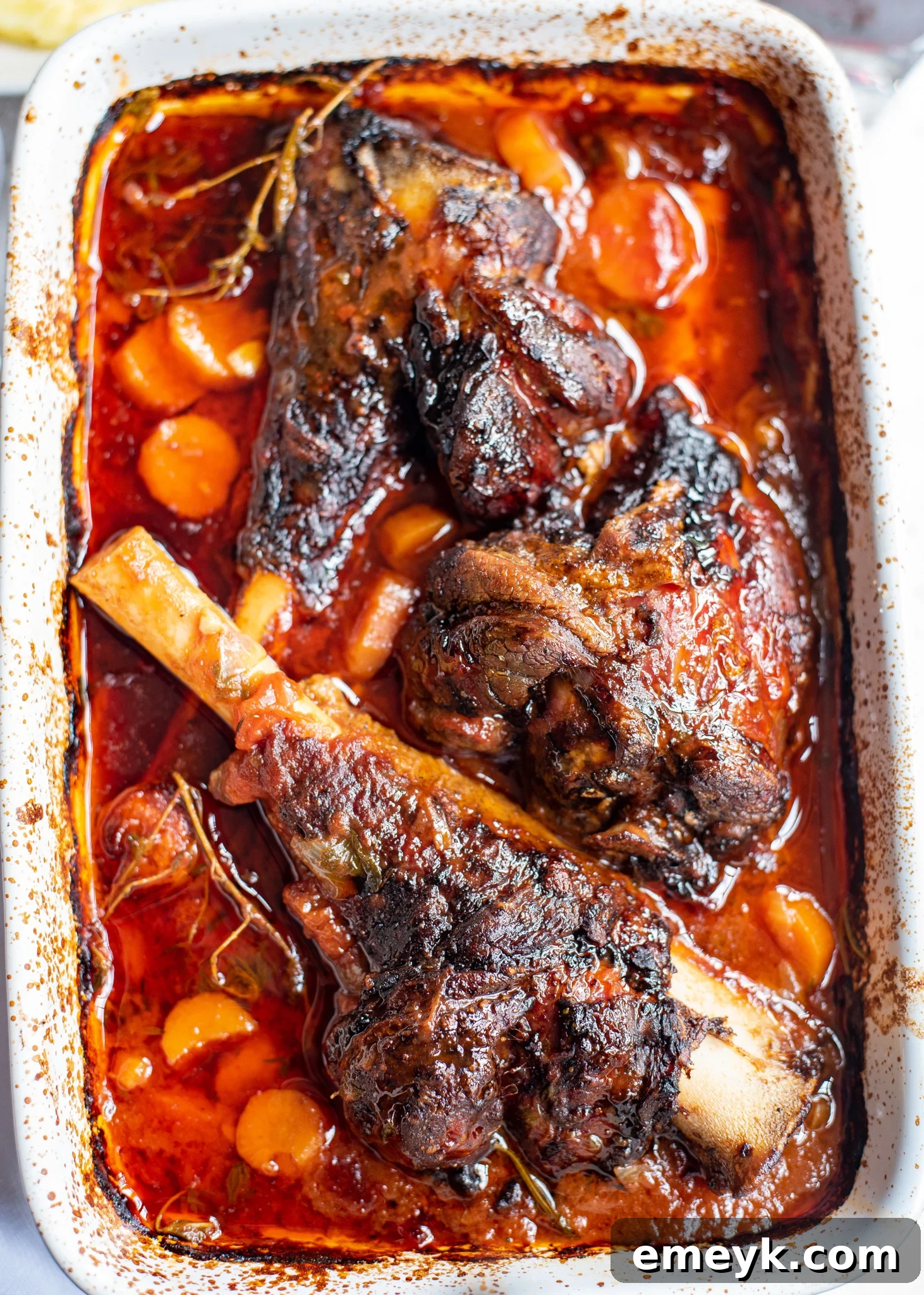 Braised Lamb Shanks Recipe placed in a white baking dish ready for the oven.