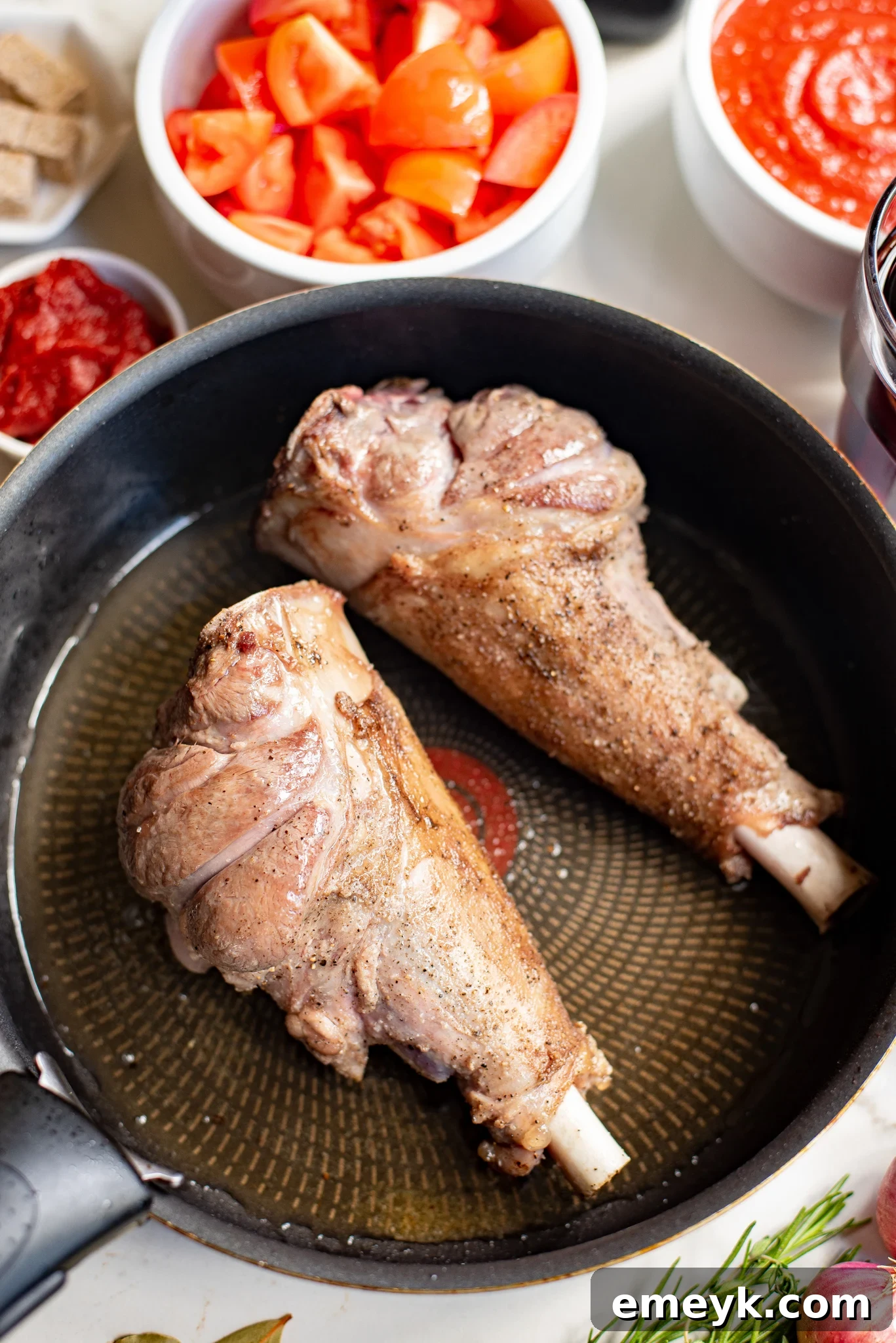 Braised Lamb Shanks Recipe lamb shanks searing in a hot skillet.