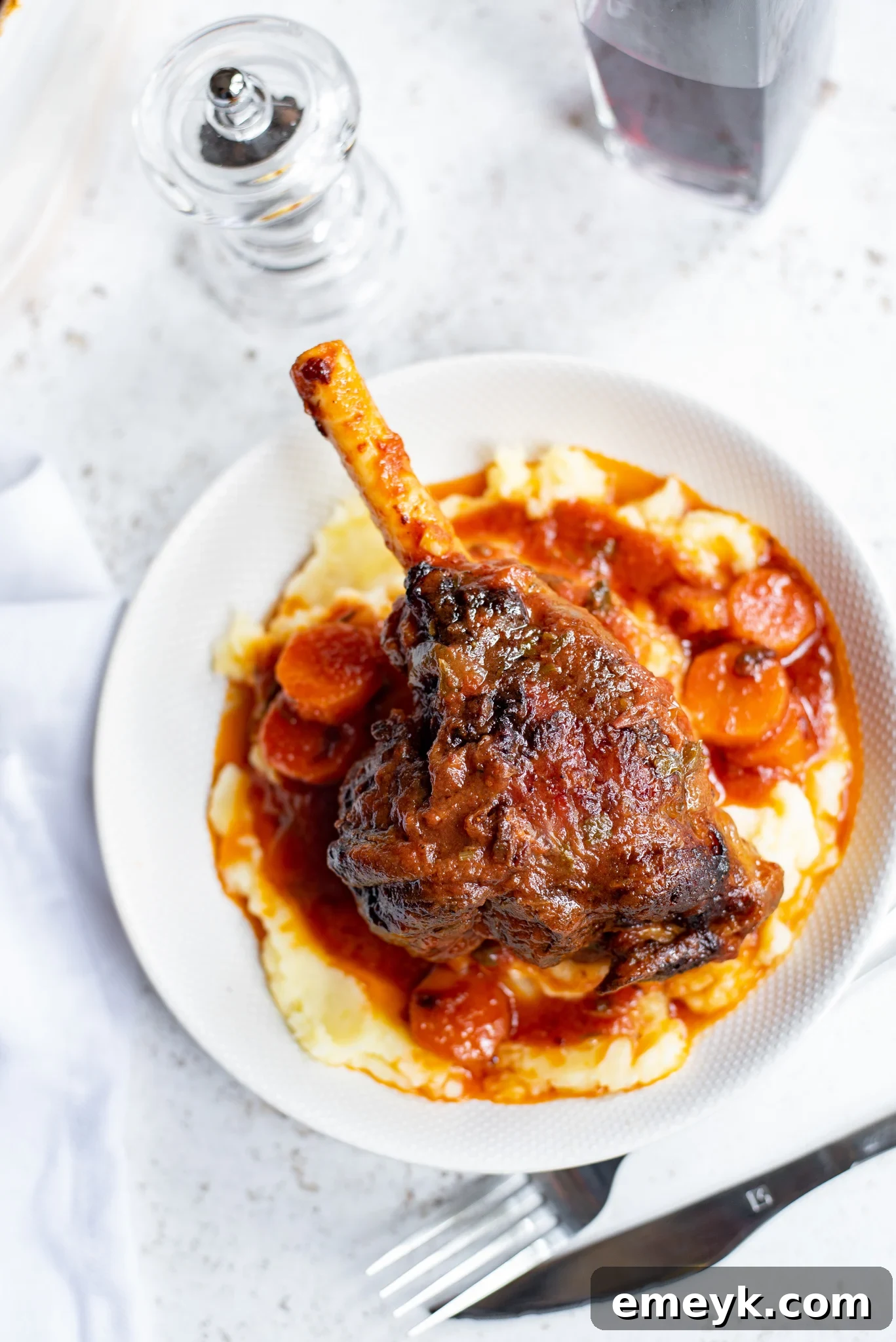 Braised Lamb Shanks Recipe served with creamy mashed potatoes and sauce.