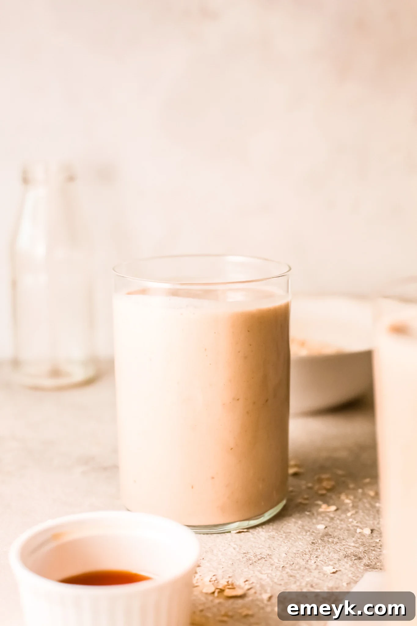 A tall glass of homemade Oat Smoothie with a straw, ready to be enjoyed.
