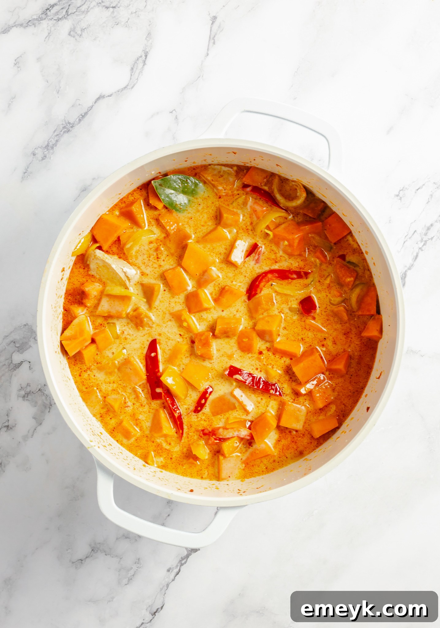 Velvety Pumpkin Curry 6 Pumpkin and vegetables simmering in coconut milk and broth in a pot for a vegan curry.