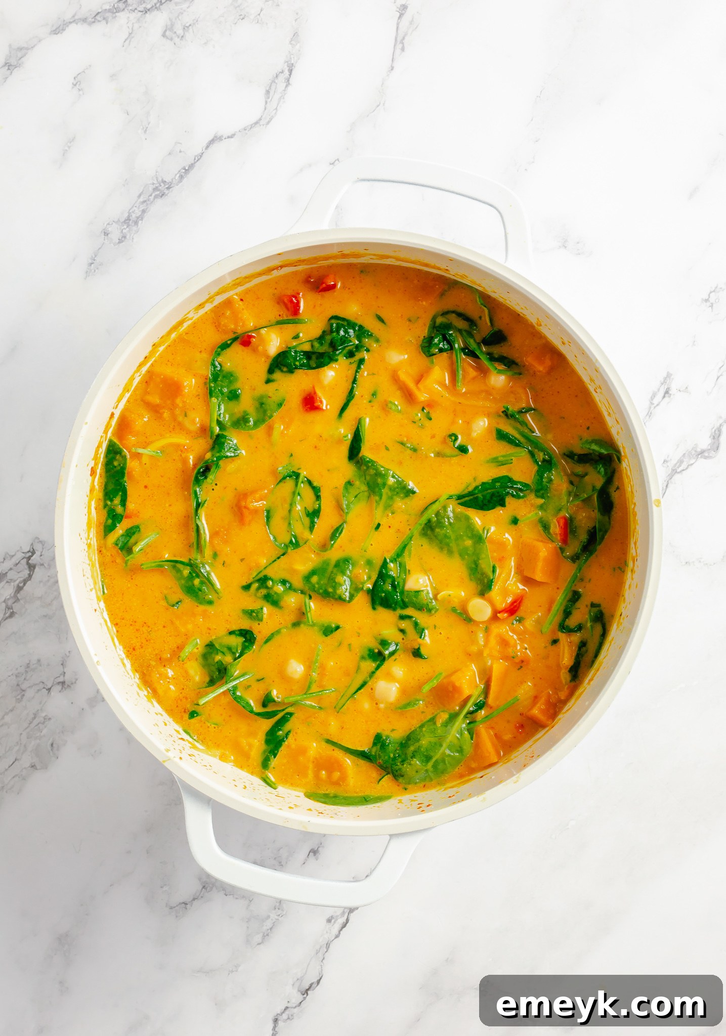 Velvety Pumpkin Curry 7 Fresh spinach being stirred into the pumpkin curry in a pot, adding vibrant color and nutrients.