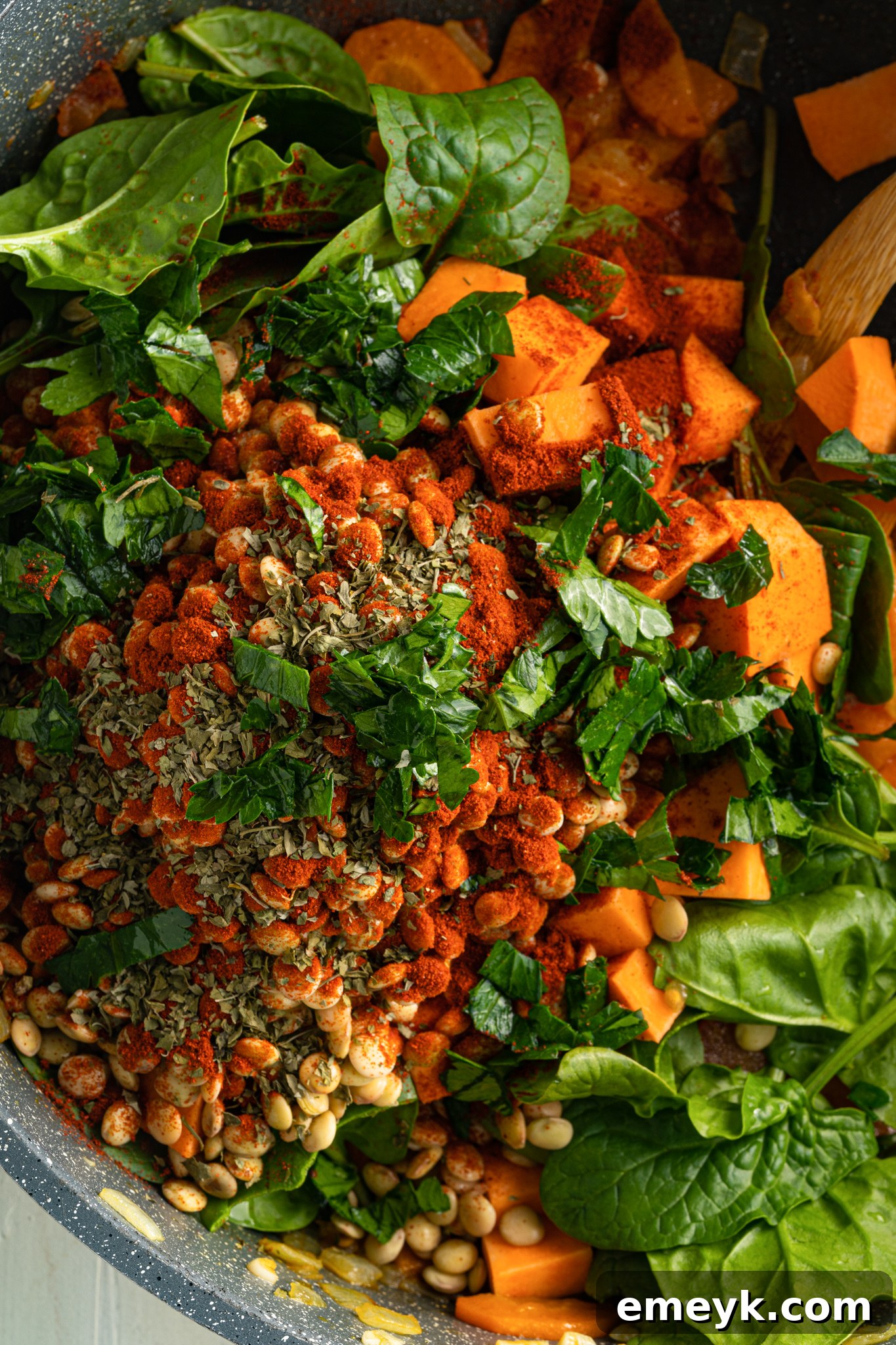 Spices being added to sautéed vegetables in a pot for Sweet Potato Lentil Soup.