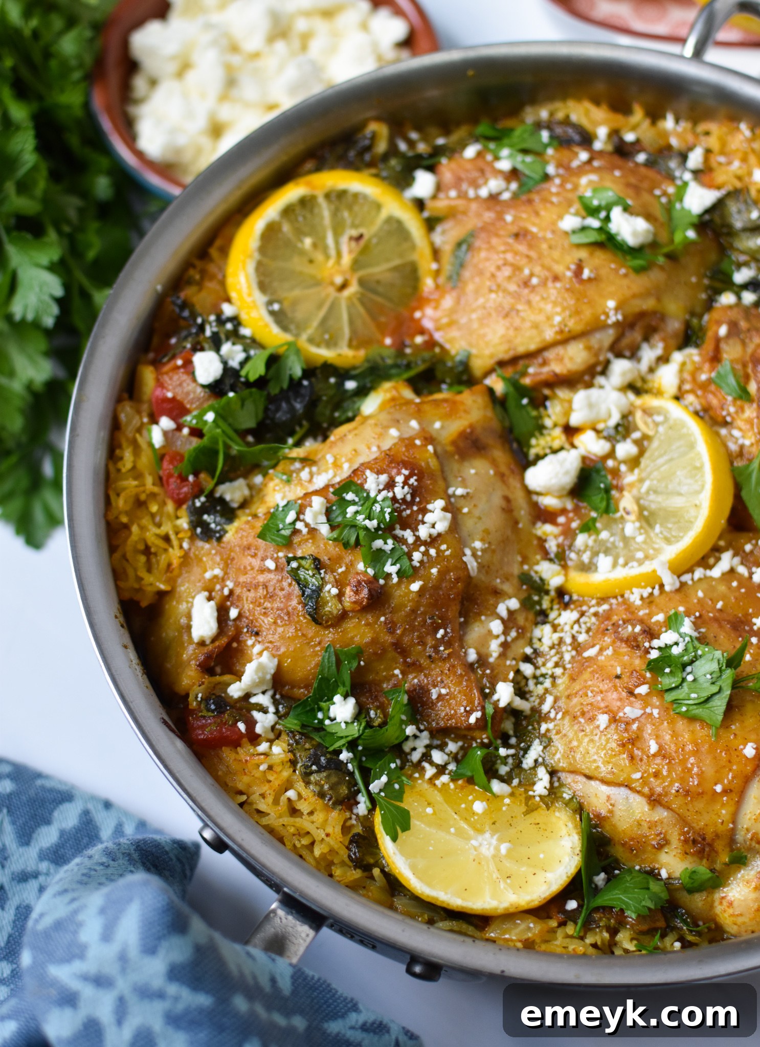 A vibrant One Pot Mediterranean Chicken and Rice dish cooking in a large pot, garnished with fresh herbs and lemon slices.