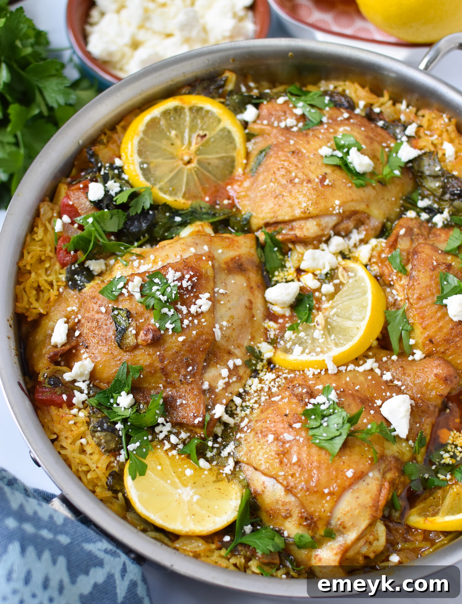 Close-up of One Pot Mediterranean Chicken and Rice in a serving dish, topped with fresh feta cheese and parsley.