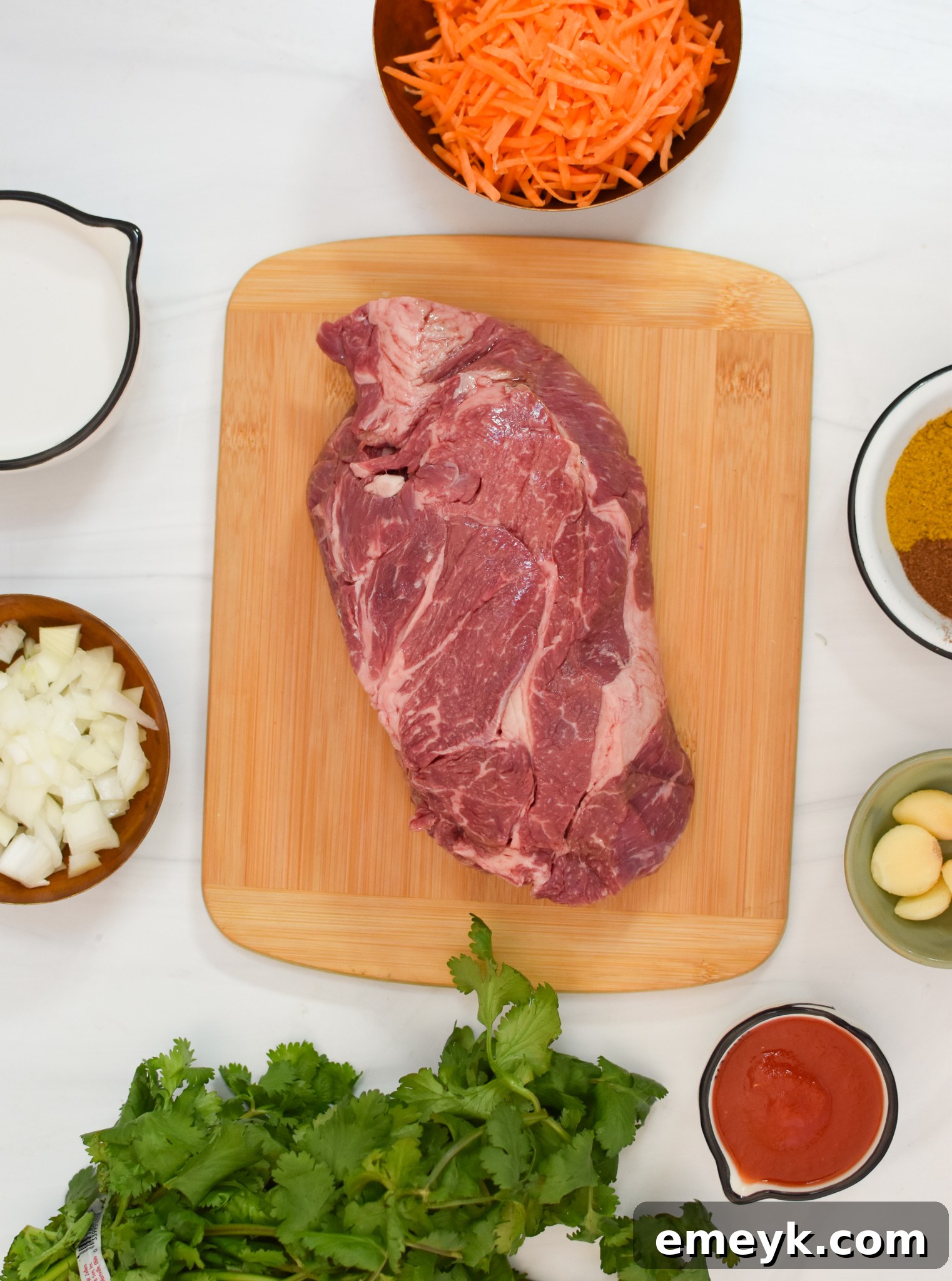Fresh ingredients laid out for Slow Cooker Beef Curry, including beef chuck roast, ginger, carrots, spices, and coconut milk.