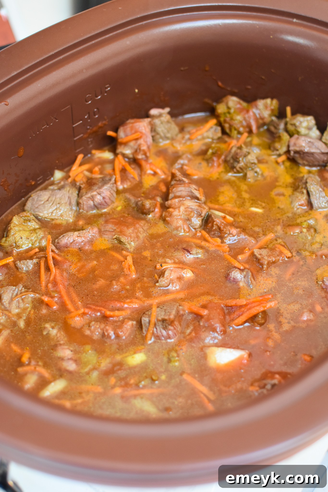 All Slow Cooker Beef Curry ingredients, including beef, vegetables, and sauce, assembled in a crockpot before cooking.