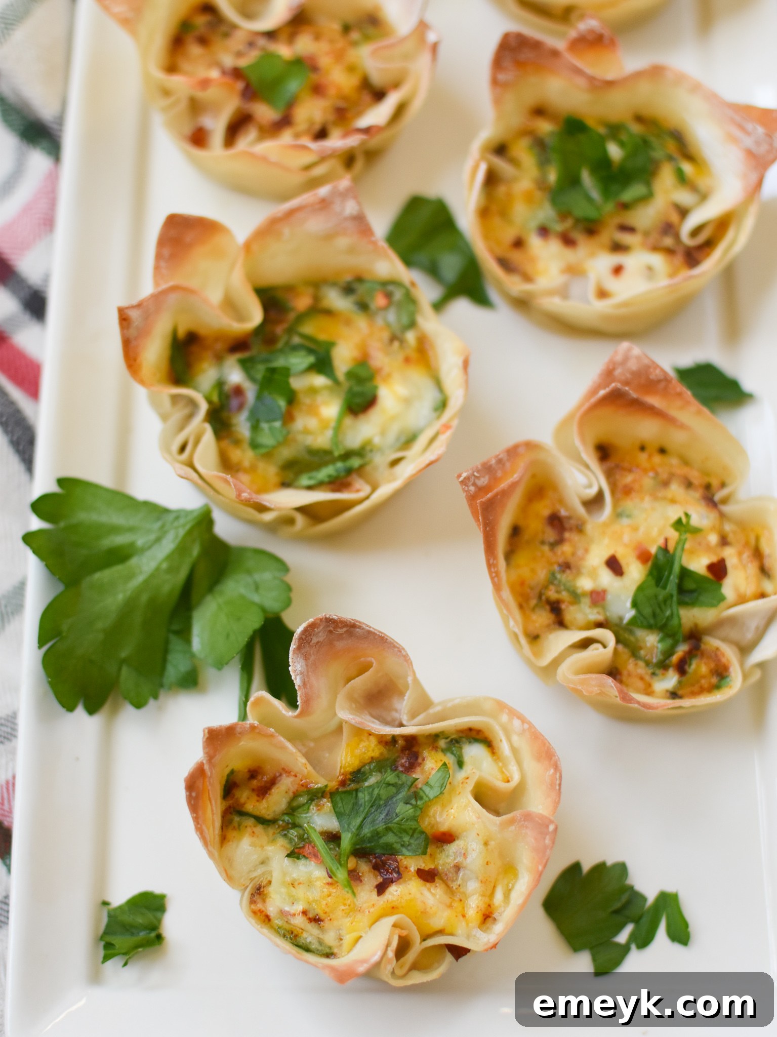 Mediterranean Quiche Pockets 4 Close-up of baked Mediterranean Quiche Wontons on a white serving plate.
