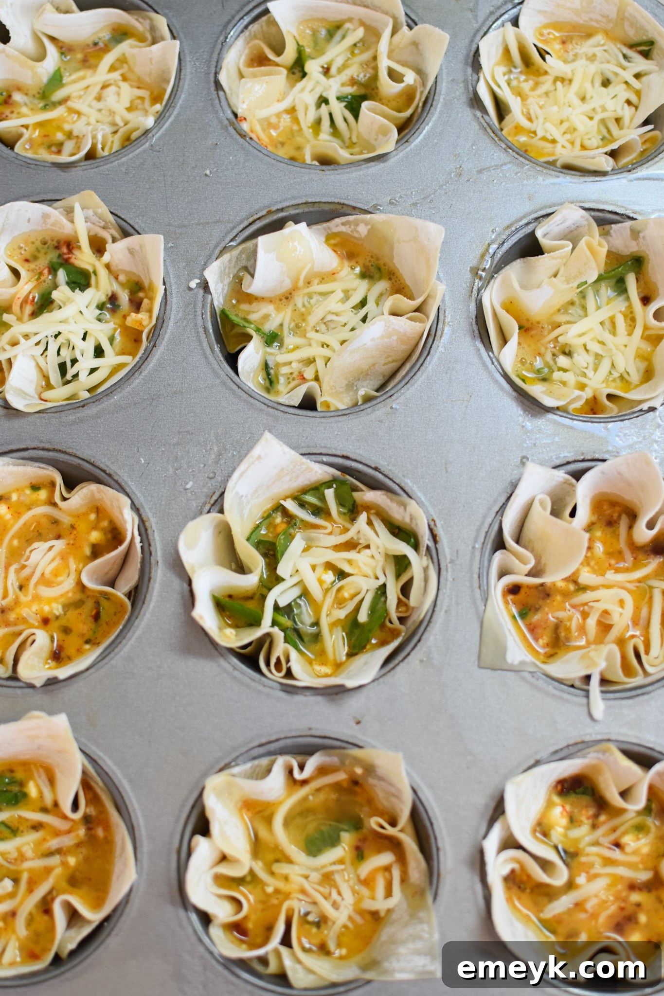 Mediterranean Quiche Pockets 7 Mediterranean Quiche Wontons baking in the muffin tin, starting to turn golden.