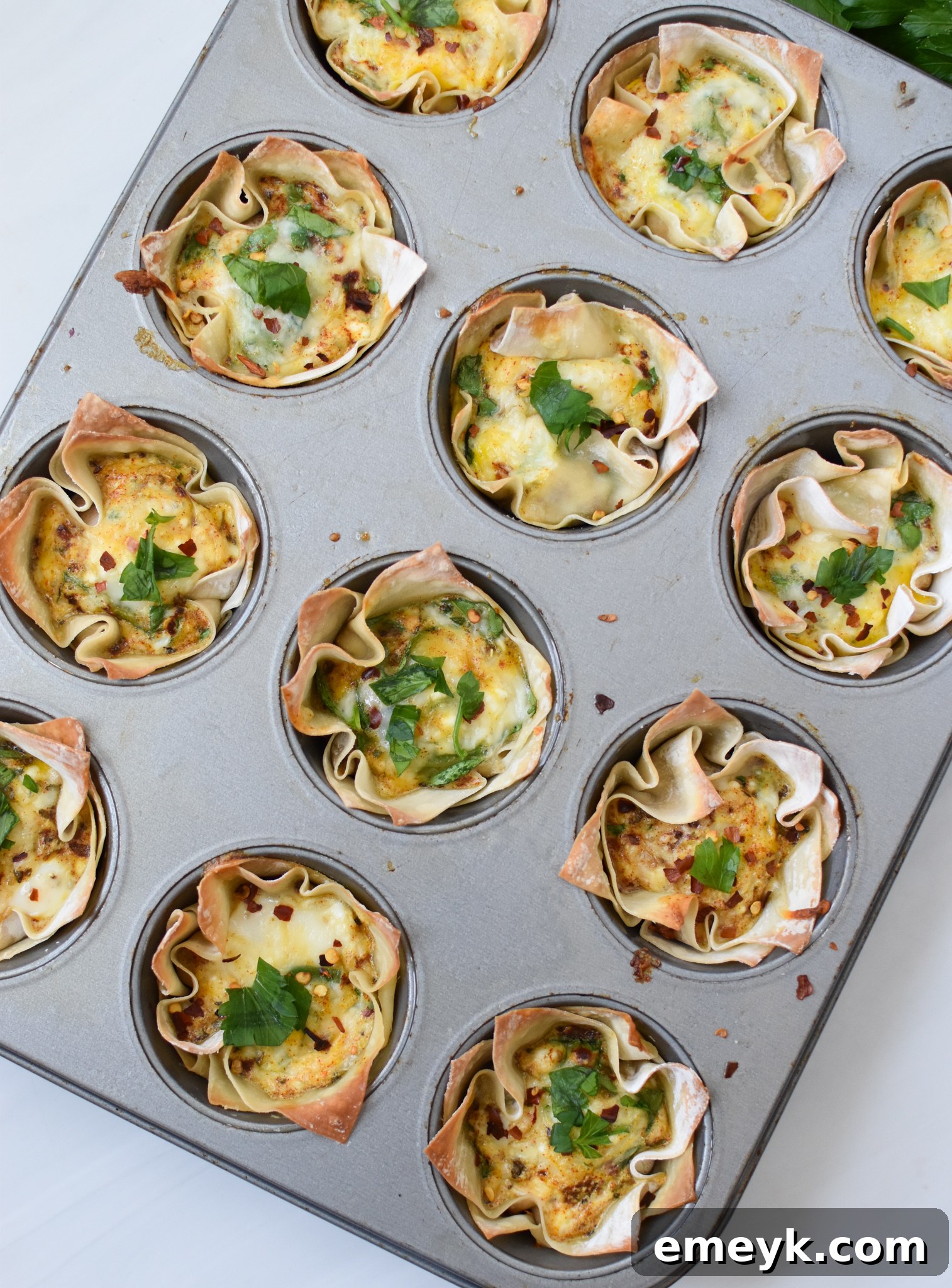 Mediterranean Quiche Pockets 8 Several Mediterranean Quiche Wontons cooling in muffin tins after baking.