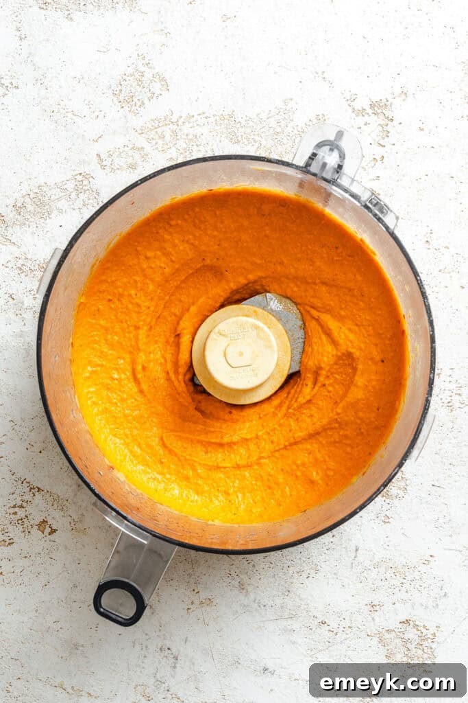 Vibrant Red Pepper Hummus 6 The food processor actively blending the Roasted Red Pepper Hummus ingredients into a smooth, consistent paste, showing the creamy transformation.