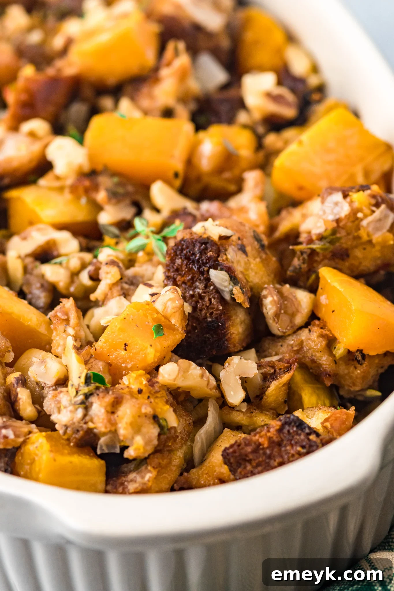 Harvest Butternut Squash Stuffing 4 Butternut Squash Stuffing in a casserole dish, garnished with fresh thyme sprigs.