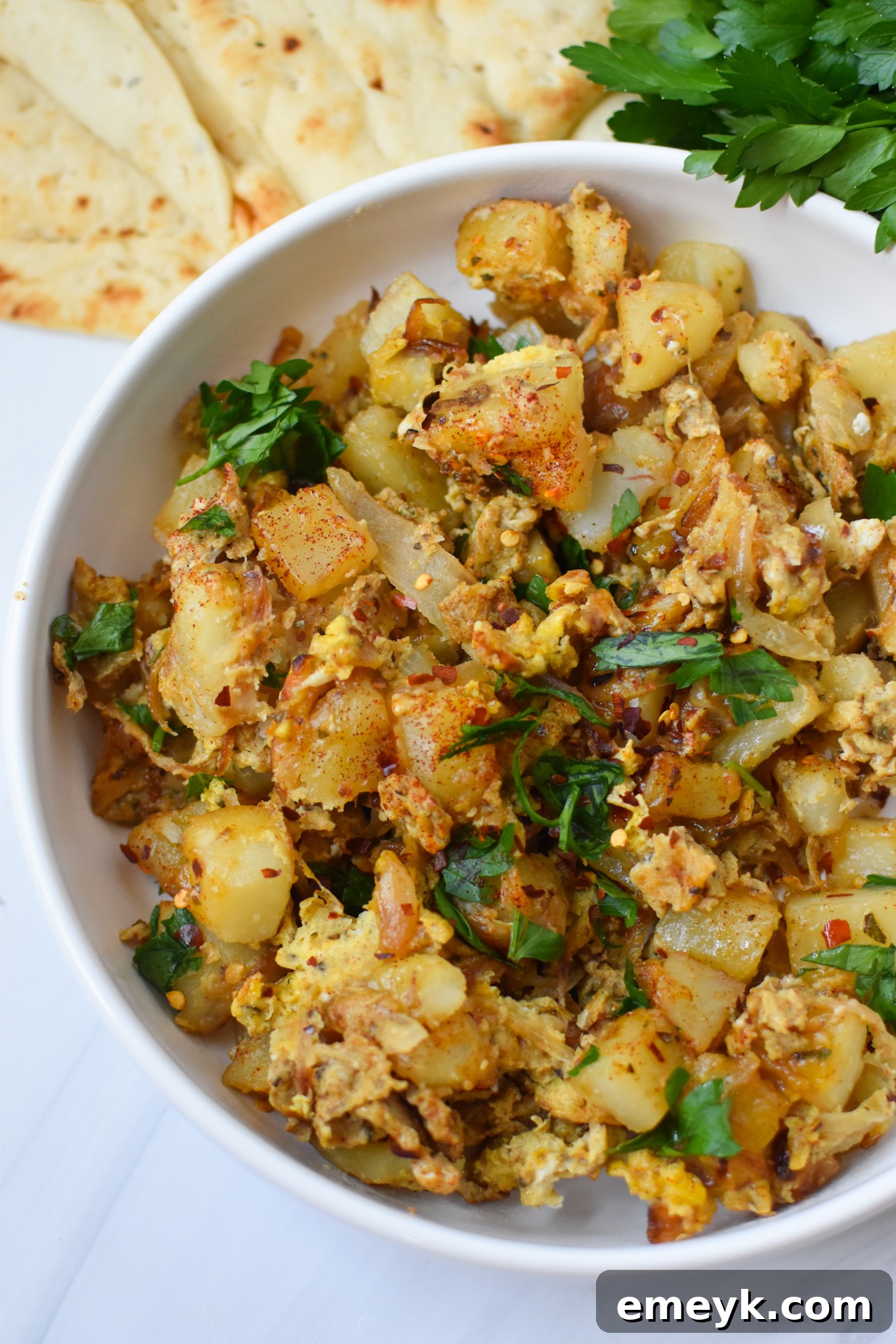 Lebanese Potato and Egg Recipe garnished with fresh parsley in a skillet.