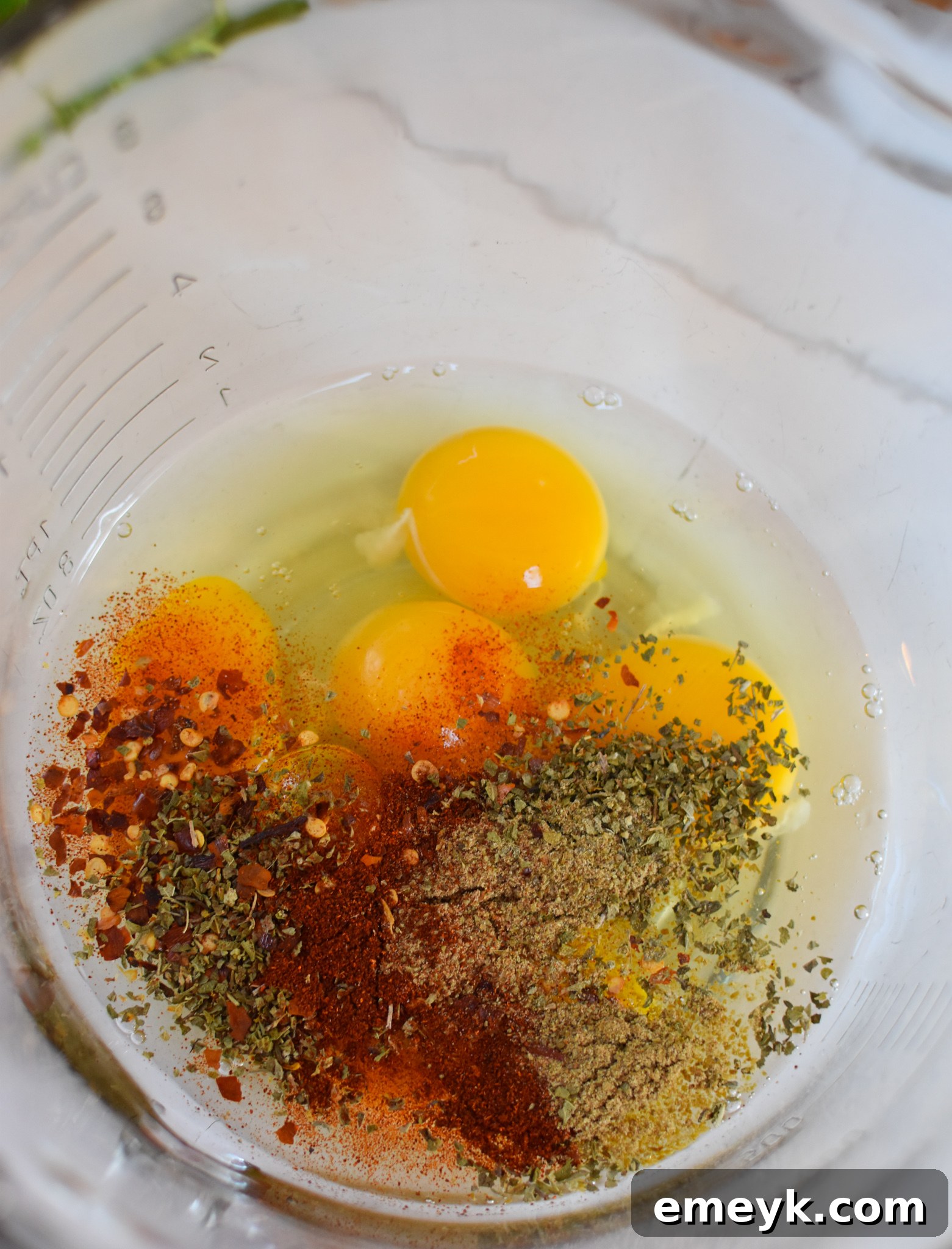 Whisked eggs with spices in a bowl.