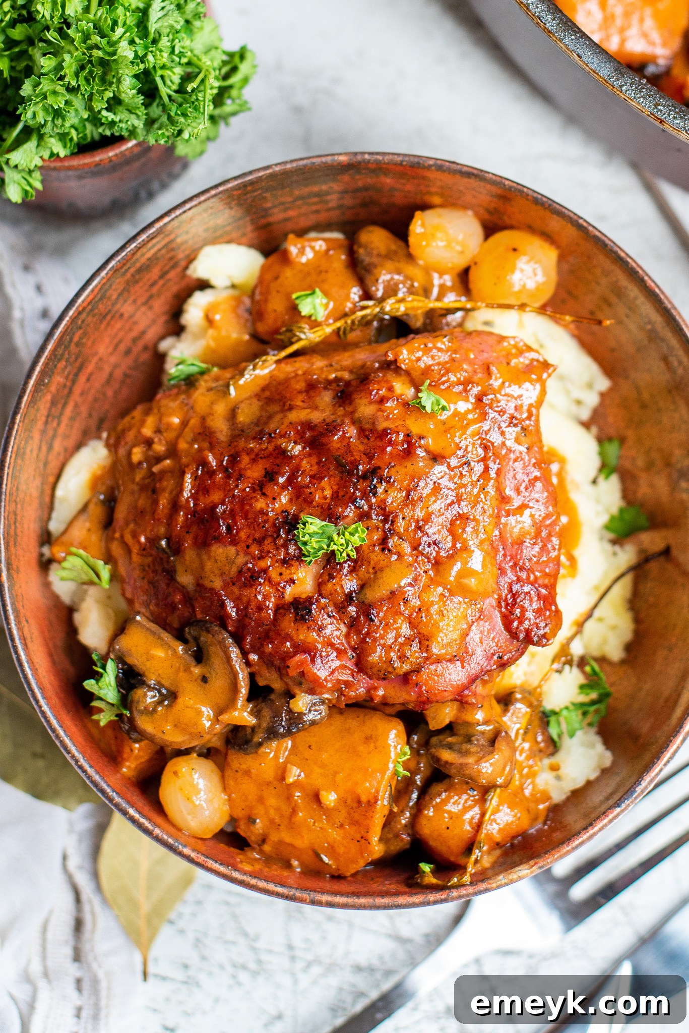 Coq au Vin Recipe served in a rustic tin bowl, garnished with fresh herbs.