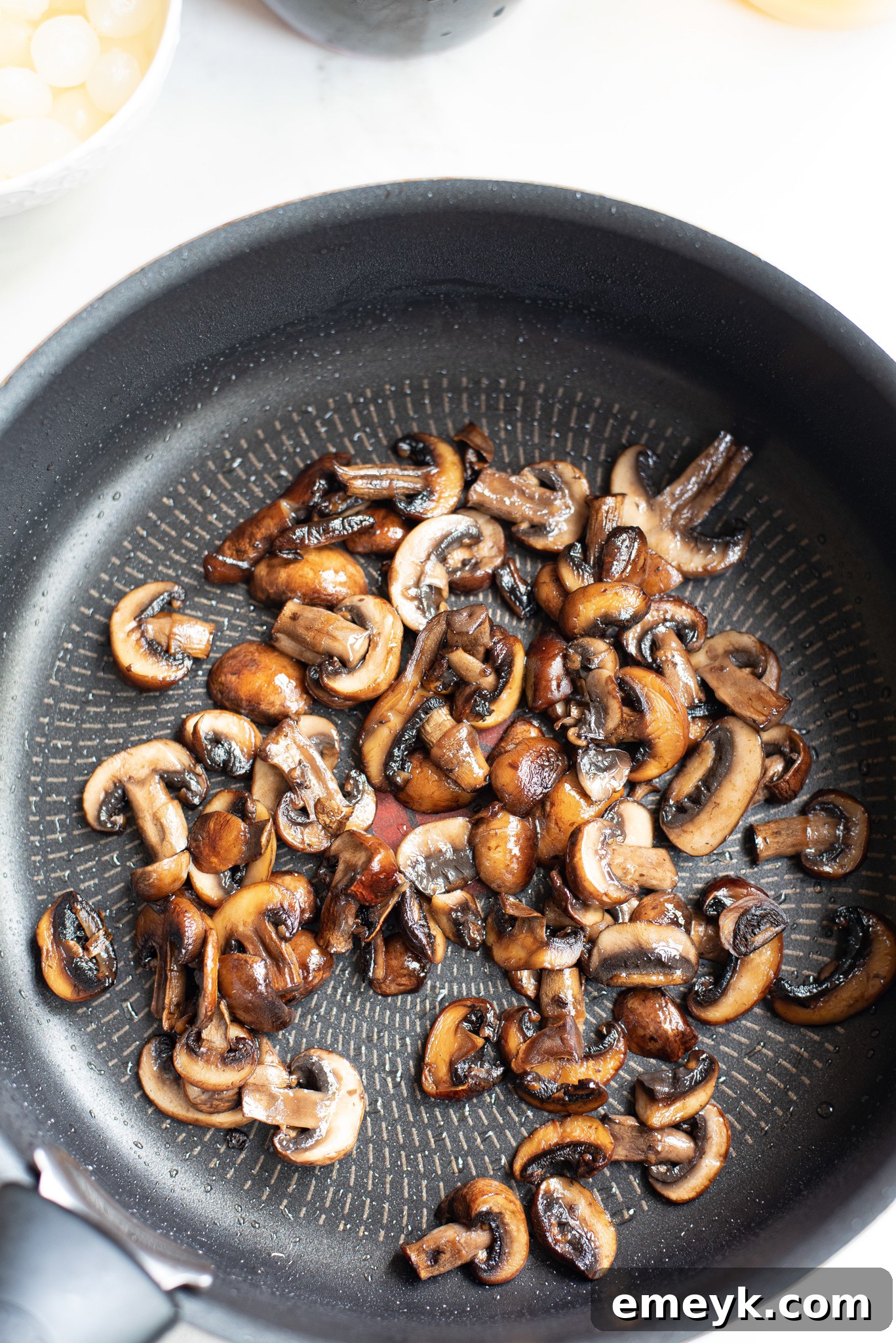 Coq au Vin Recipe: Sautéing mushrooms in a skillet, essential for depth of flavor.