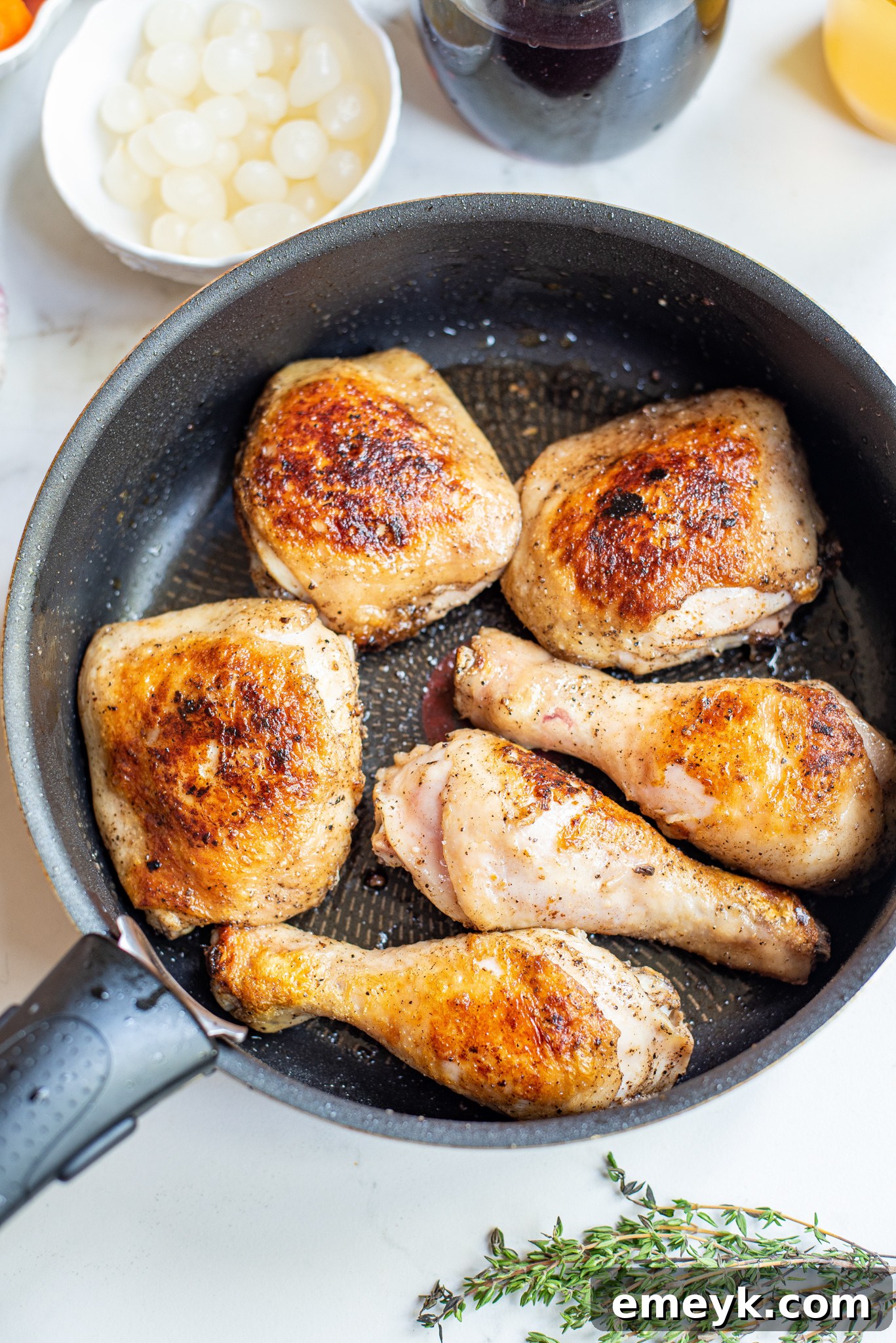Coq au Vin Recipe: Browning chicken pieces in a Dutch oven for a crispy skin.