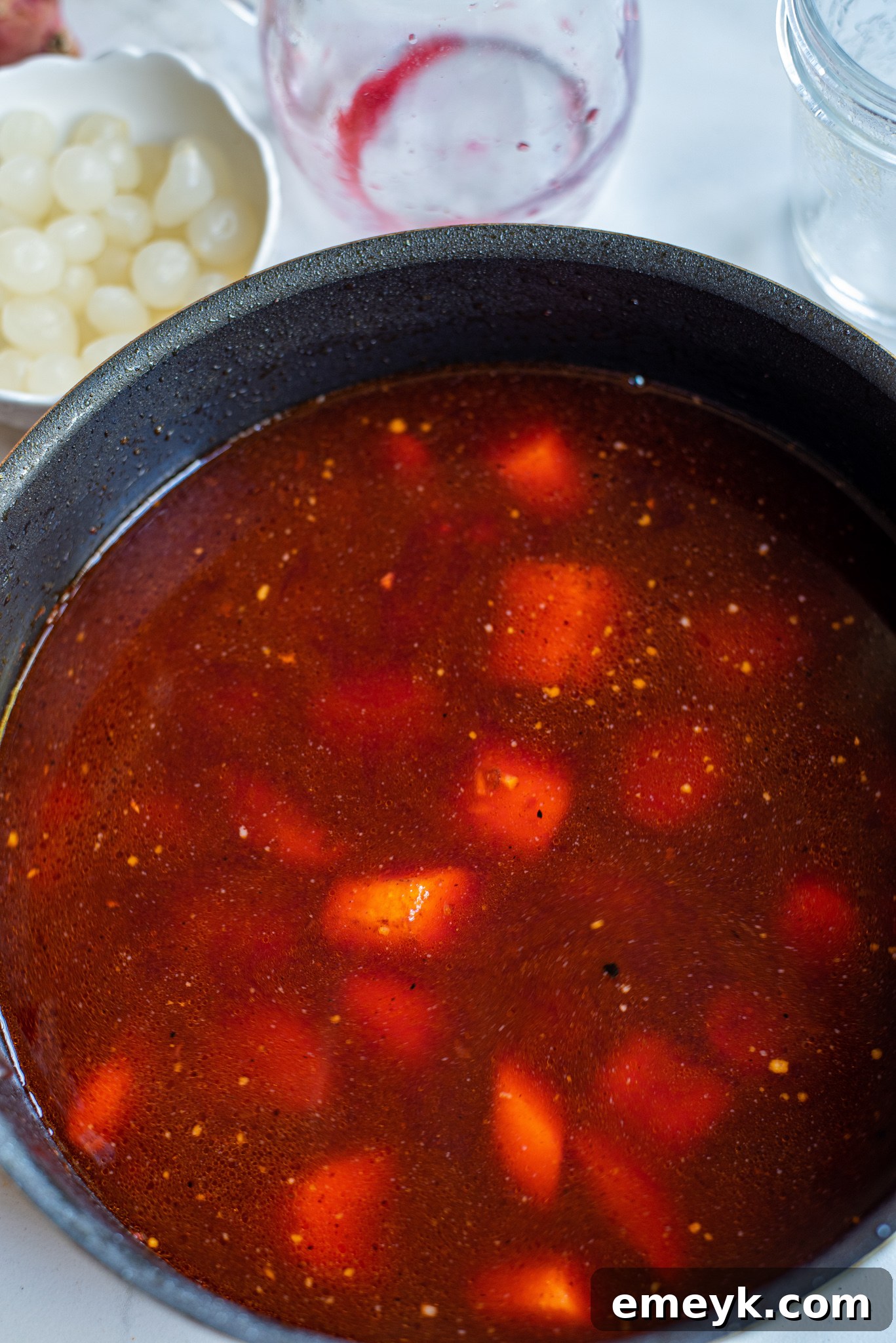 Coq au Vin Recipe: Red wine and onions simmering in a Dutch oven, forming the stew base.