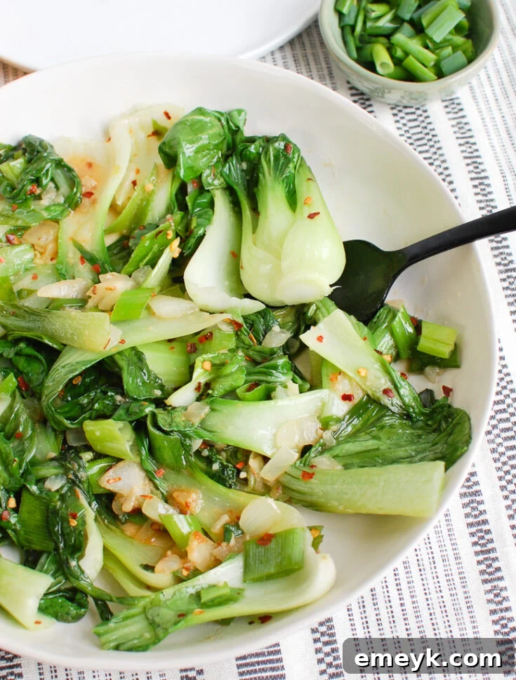 Perfectly sautéed Easy Bok Choy Recipe, with tender green leaves and crisp white stalks, presented simply in a white bowl.