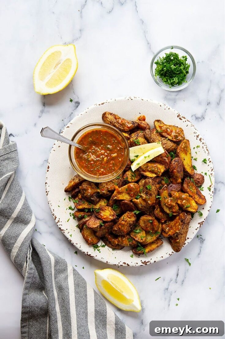 Crispy Air Fryer Fingerling Potatoes, golden brown and perfectly cooked, topped with a vibrant green Harissa Chimichurri sauce.