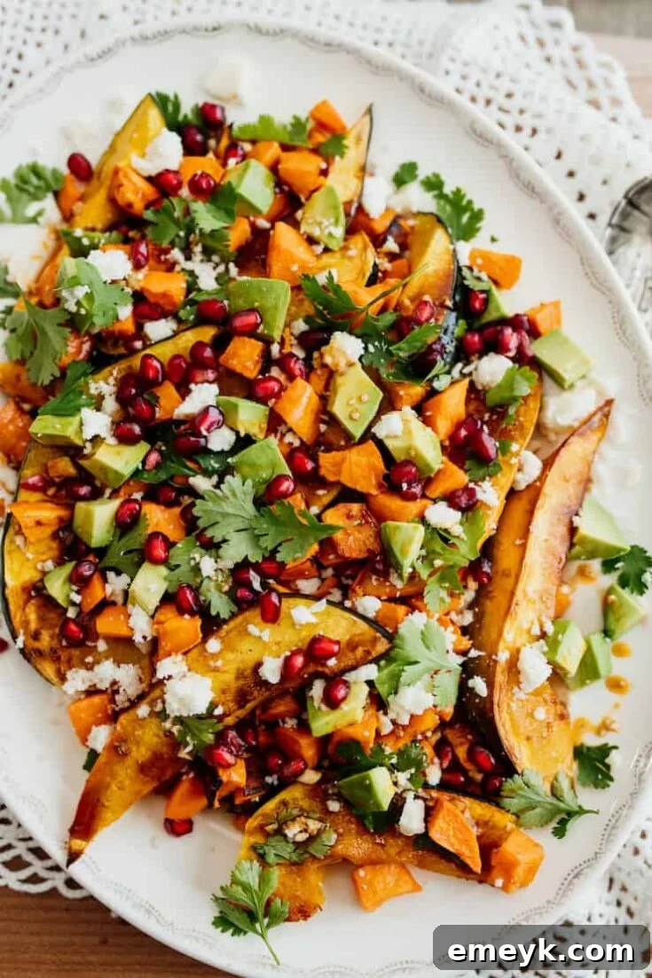 A hearty and visually appealing Roasted Sweet Potato and Acorn Squash Winter Salad, studded with vibrant pomegranate seeds and fresh greens.