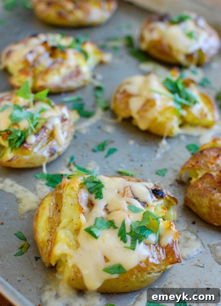 Close-up of golden and crispy Gouda Smashed Potatoes, garnished with fresh green herbs, showcasing their irresistible texture.