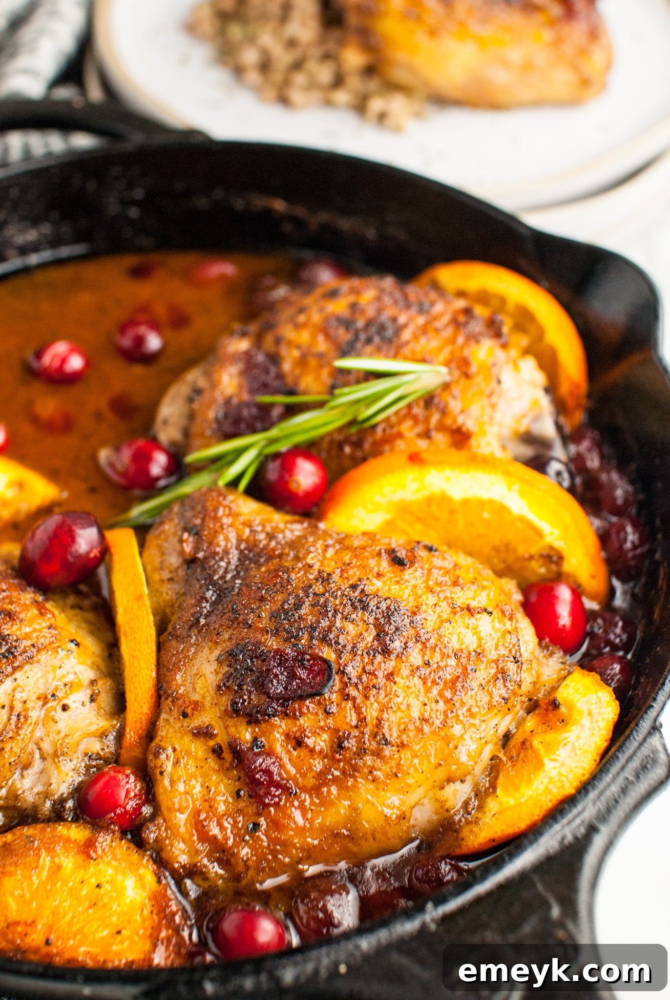Easy Baked Chicken Thighs in a cast iron skillet with cranberry orange glaze before baking.