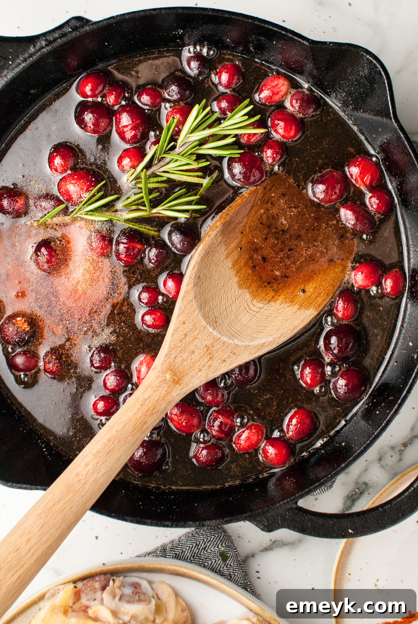 Cranberry orange sauce simmering in a cast iron skillet.