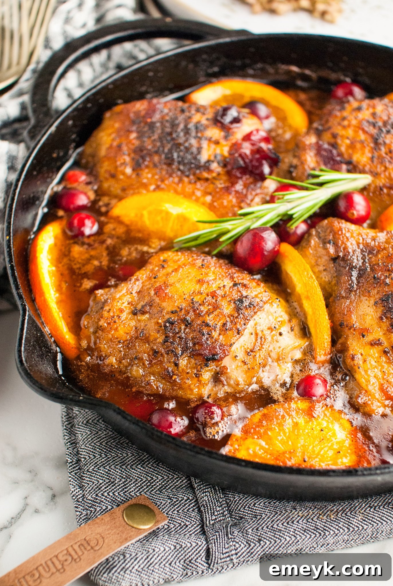 Easy Baked Chicken Thighs garnished with fresh rosemary on a white serving plate.