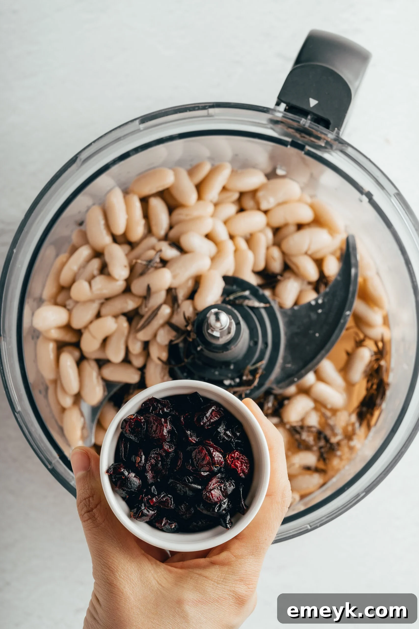 All the ingredients for White Bean Hummus with Cranberry, including the infused oil, being blended to a smooth consistency in a food processor.