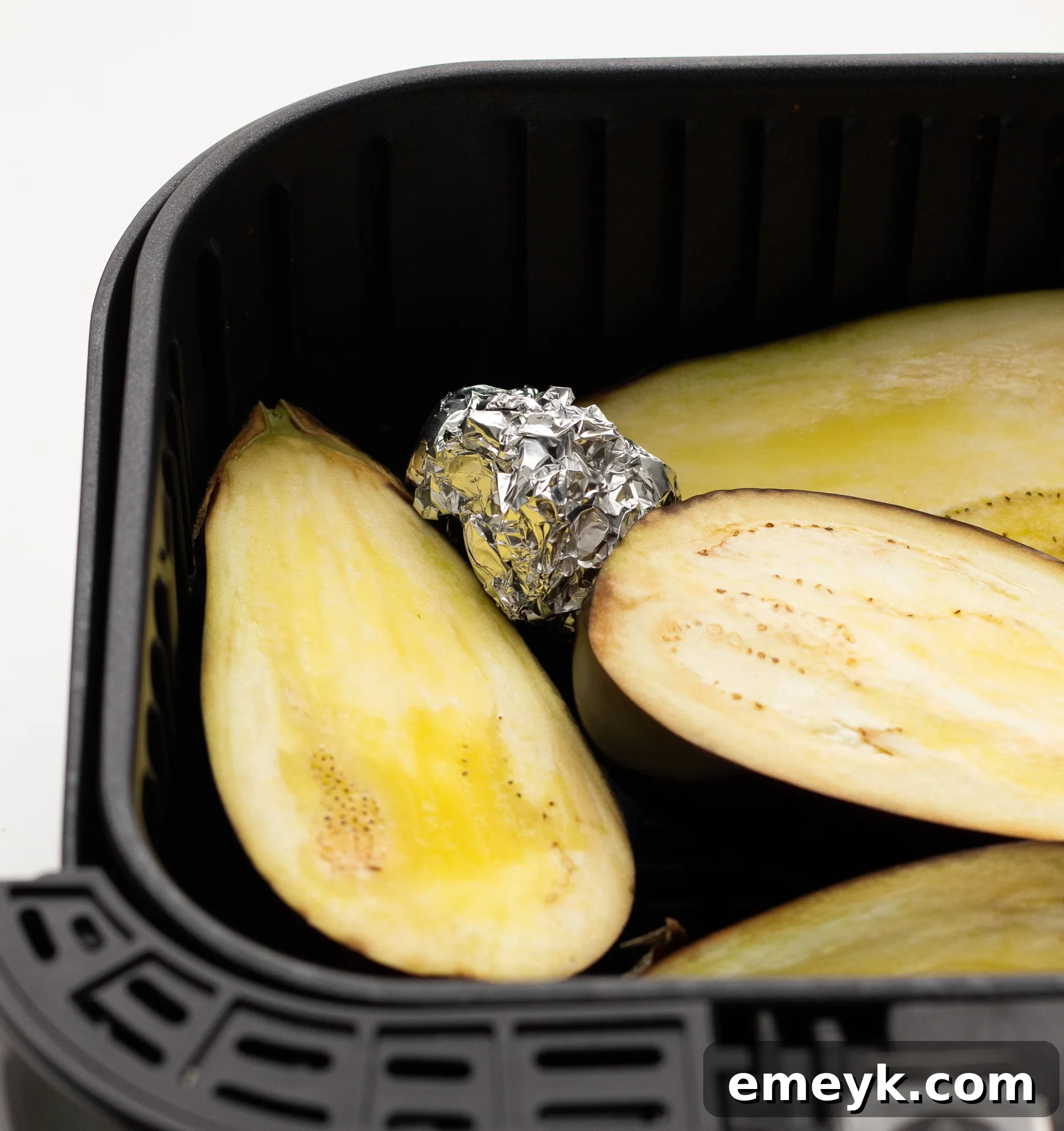 Air Fryer Eggplant cooking in the air fryer with garlic cloves, adding aroma and flavor.