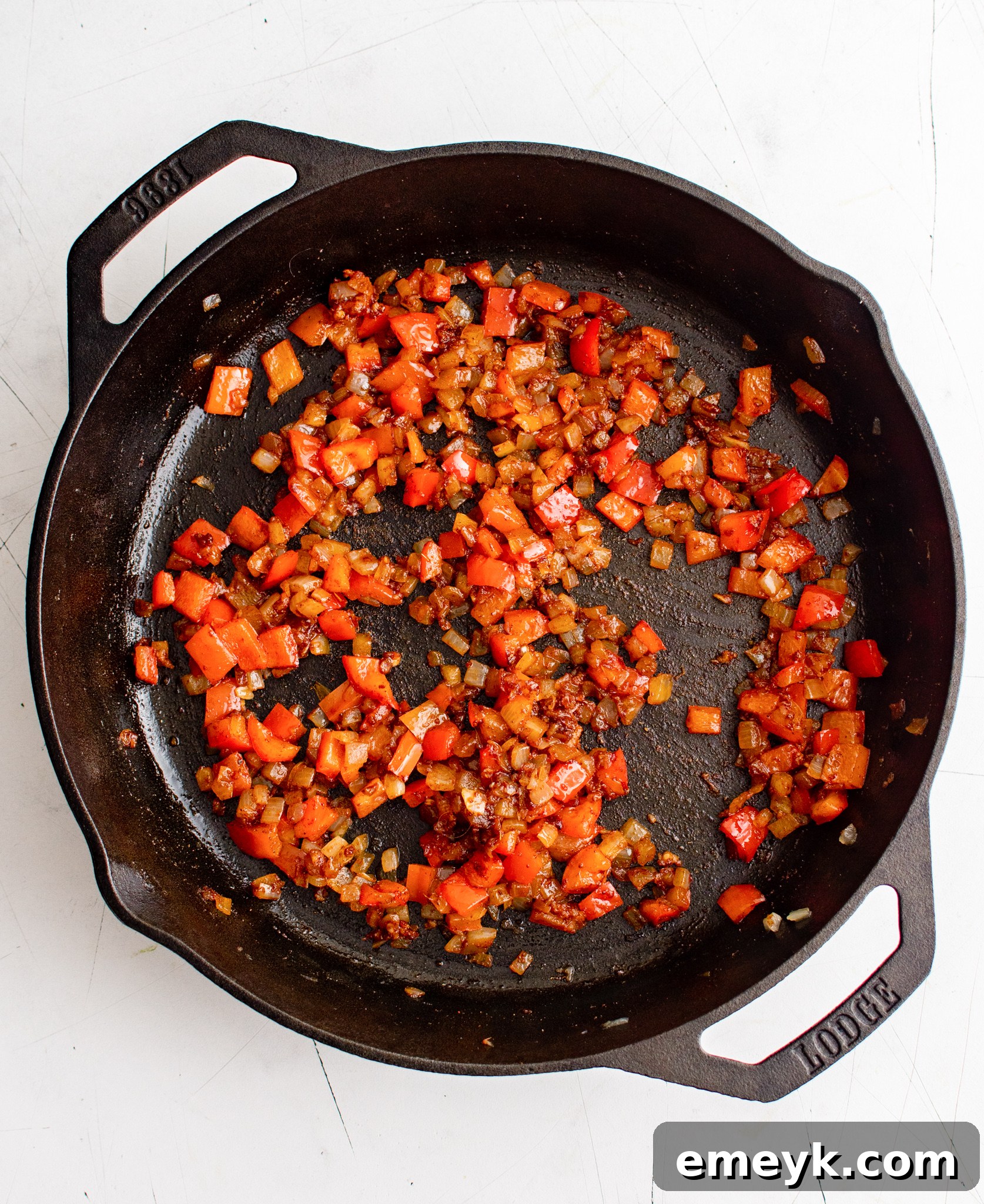 Bell peppers, onions, and spices sautéing in a skillet for shakshuka.