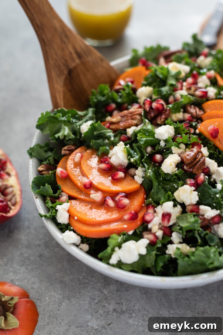 Elegant Holiday Salad with vibrant kale, sweet persimmon slices, and jewel-like pomegranate arils, dressed for a festive occasion.