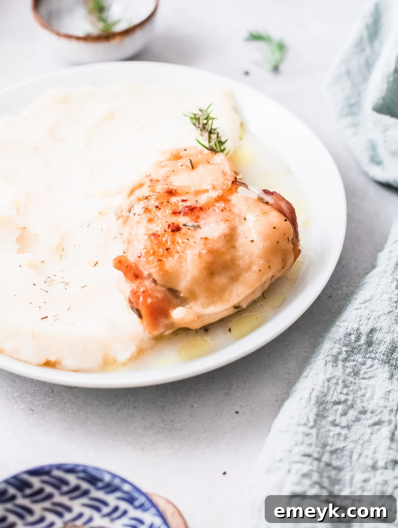 Instant Pot Creamy Rosemary Chicken on a white plate, garnished with fresh rosemary.
