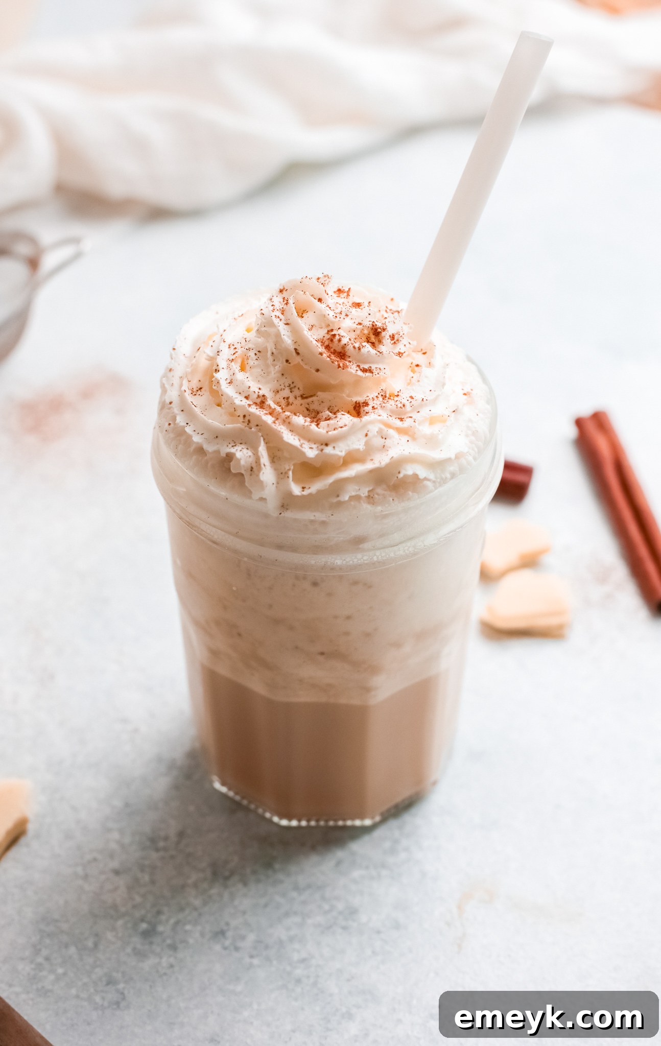 A refreshing White Chocolate Frappuccino served in a clear glass, topped with a generous swirl of whipped cream and a single straw.