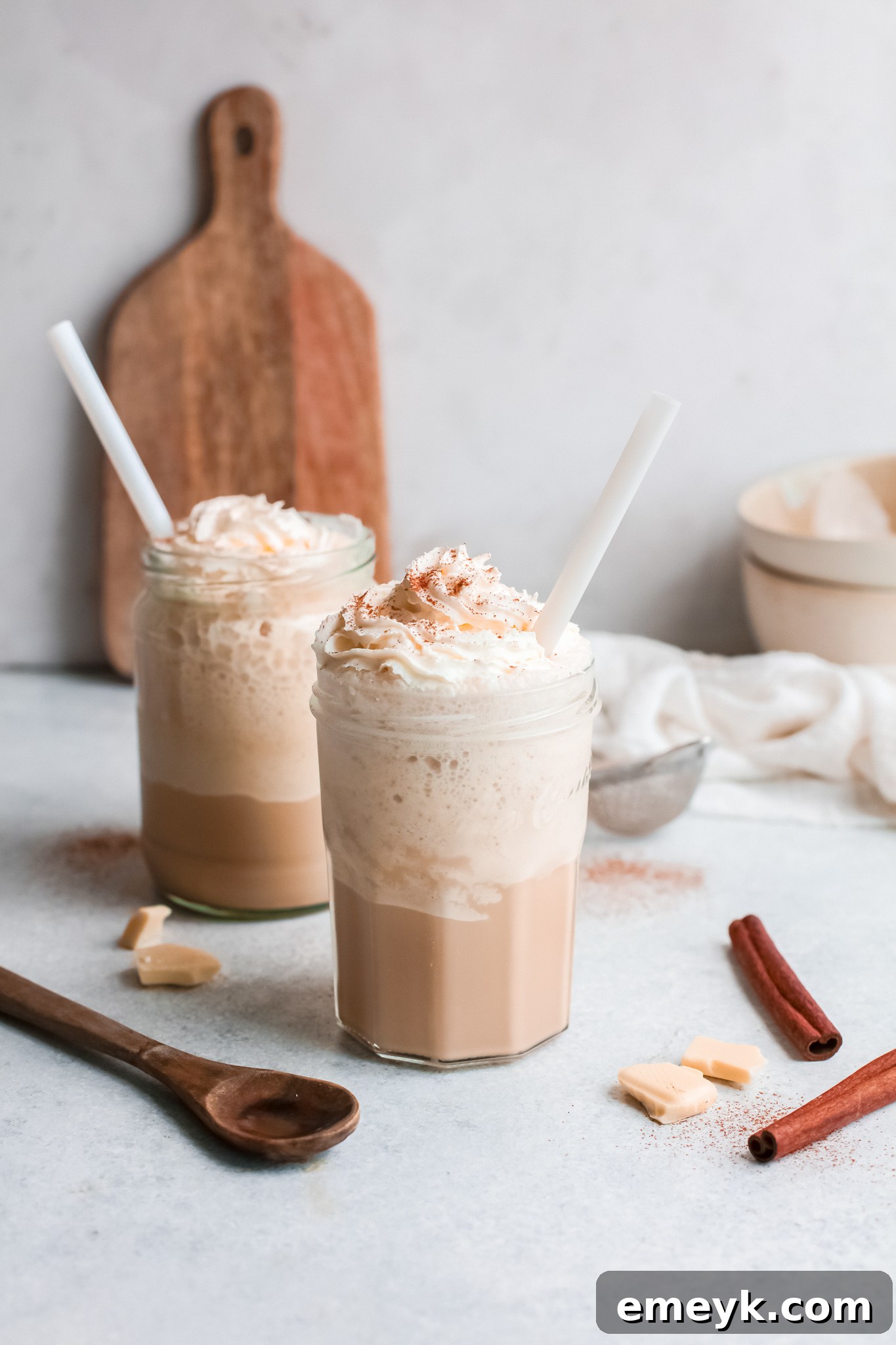Close-up of a White Chocolate Frappuccino in a stylish glass, garnished with a generous dollop of whipped cream and two straws.