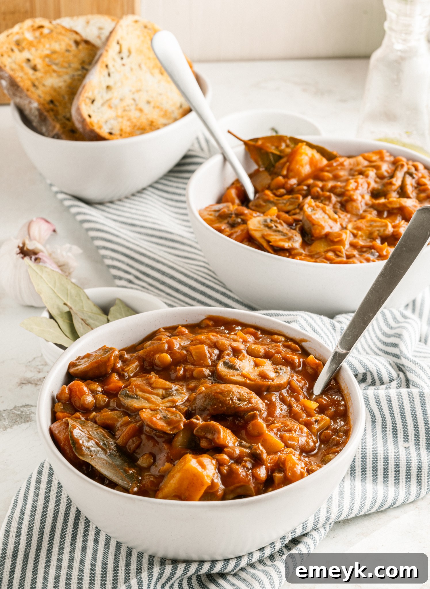 Hearty Lentil Mushroom Stew 10 Two bowls of Lentil Mushroom Stew on a rustic table setting.