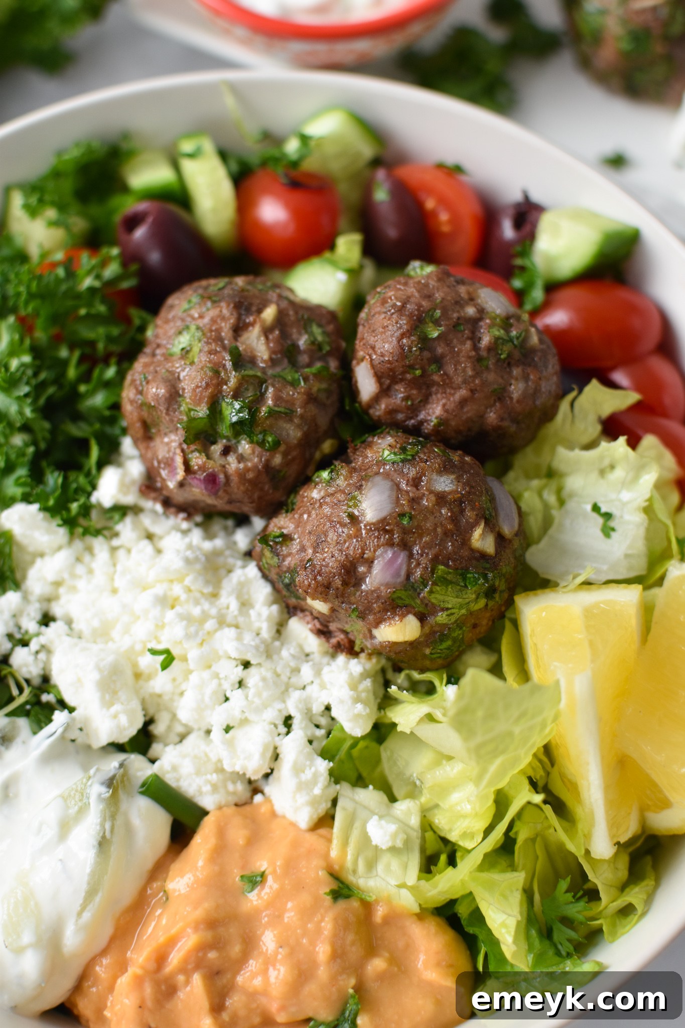 Prepared Mediterranean Baked Beef Meatballs in a vibrant hummus bowl, ready to serve.