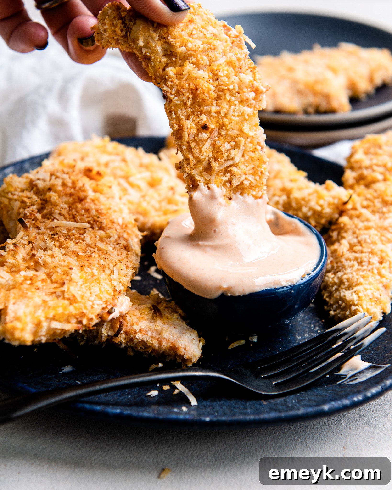Air Fryer Coconut Chicken Tenders served with a small dish of dipping sauce.
