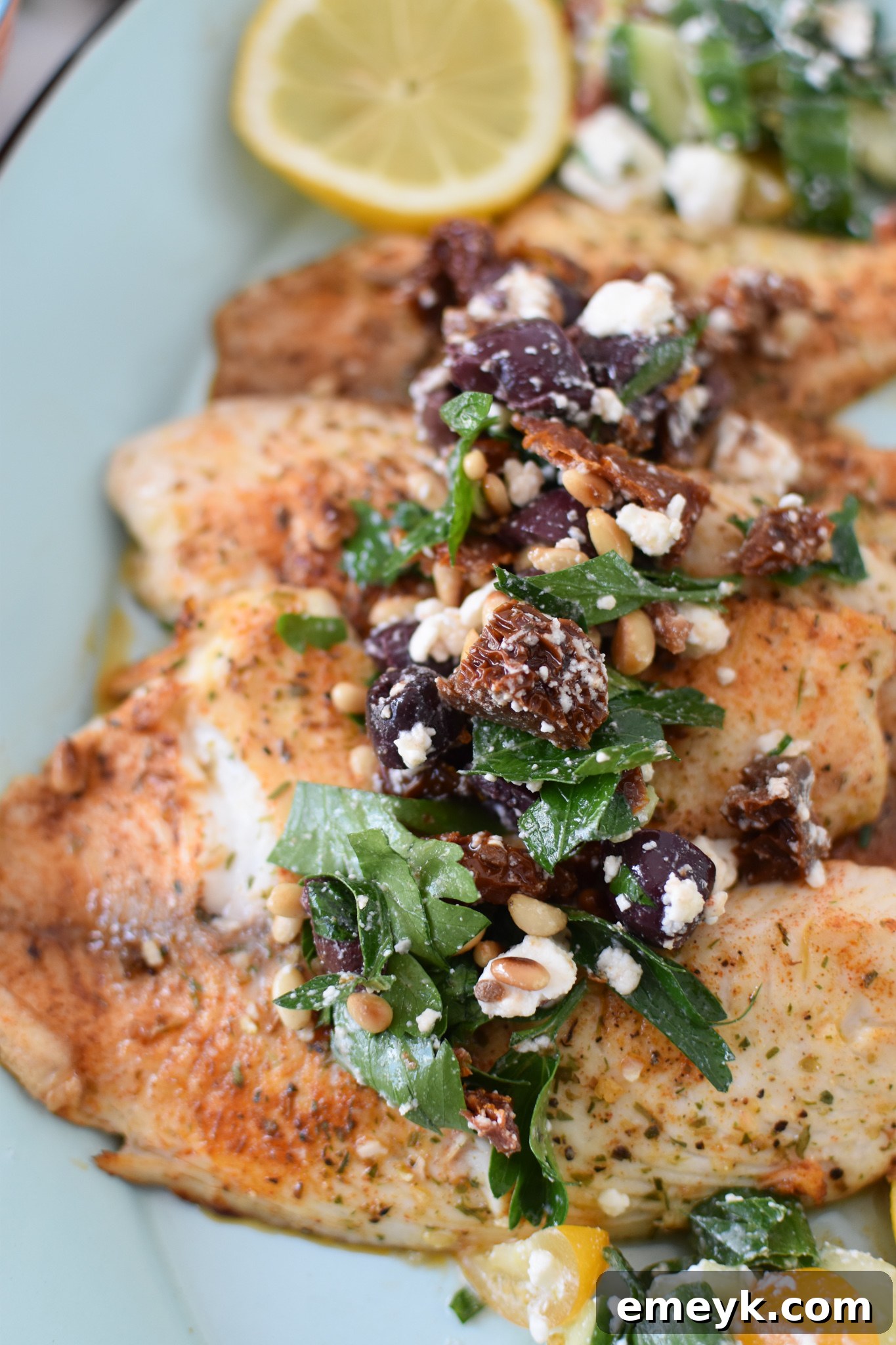 Close-up of Greek Baked Tilapia fillets in a cast iron skillet, ready for baking.