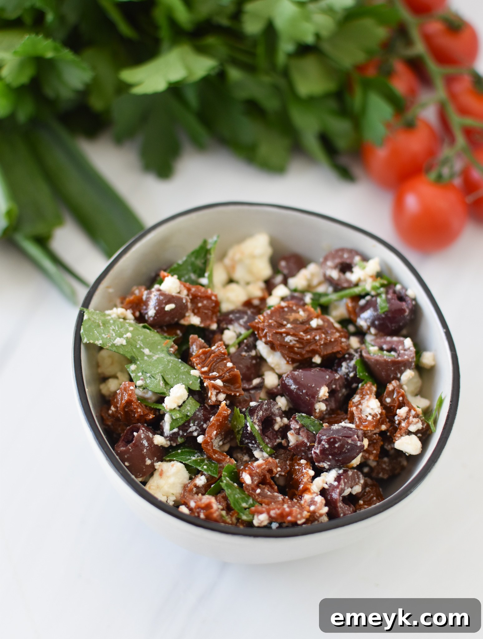 Close-up of homemade olive tapenade with feta, sun-dried tomatoes, and pine nuts.