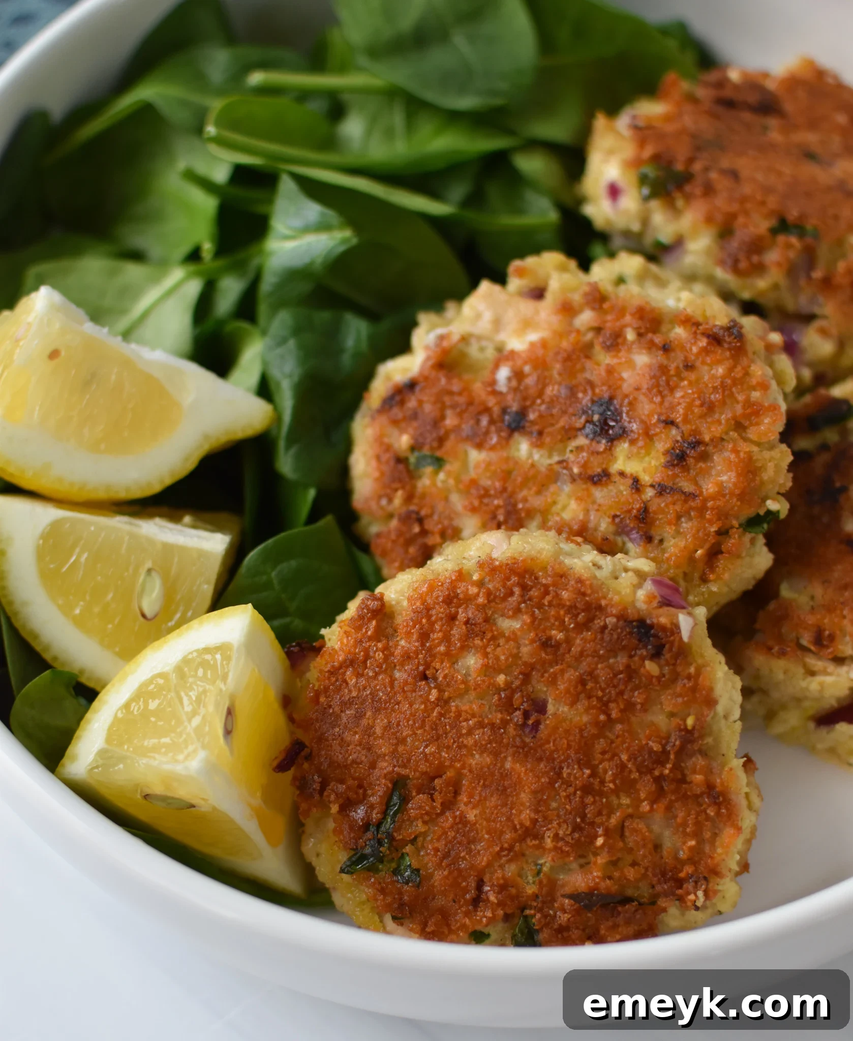 Sun Kissed Mediterranean Tuna Fritters 2 Mediterranean Tuna Patties Recipe in a white bowl, garnished with fresh herbs.
