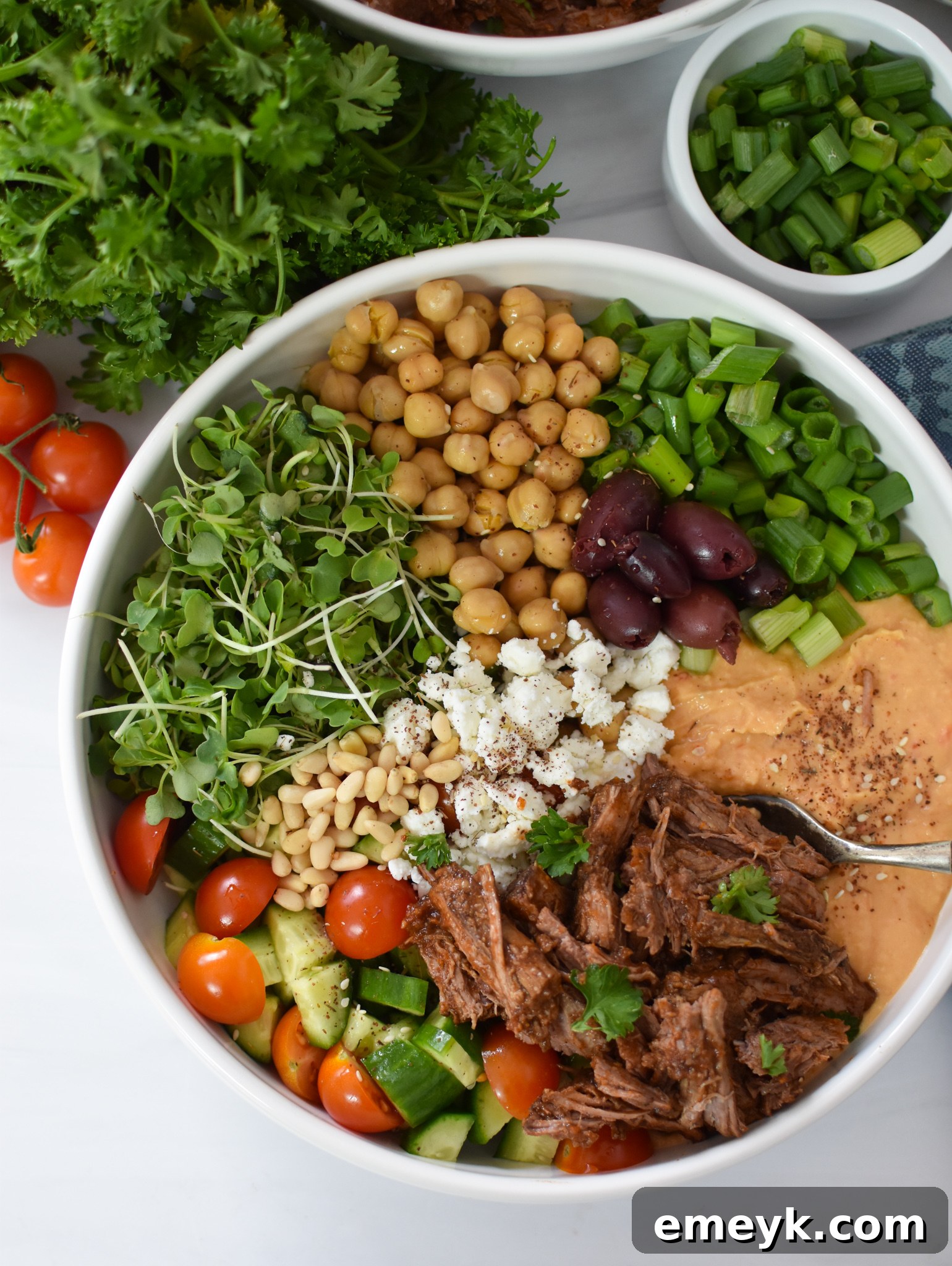 Fresh olives and creamy hummus, essential toppings for a Mediterranean hummus bowl.