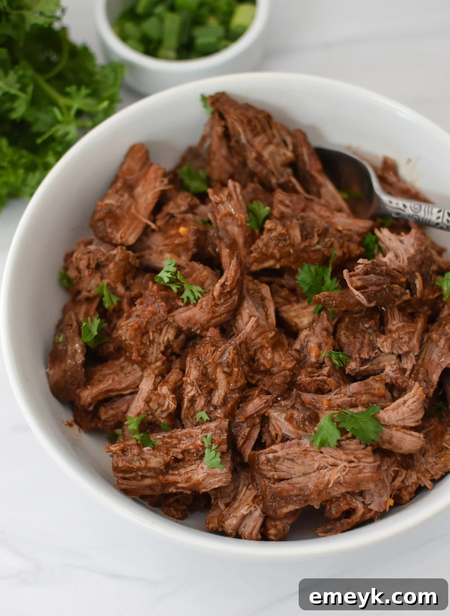 Assembling a Slow Cooker Shredded Beef Hummus Bowl with all fresh toppings.