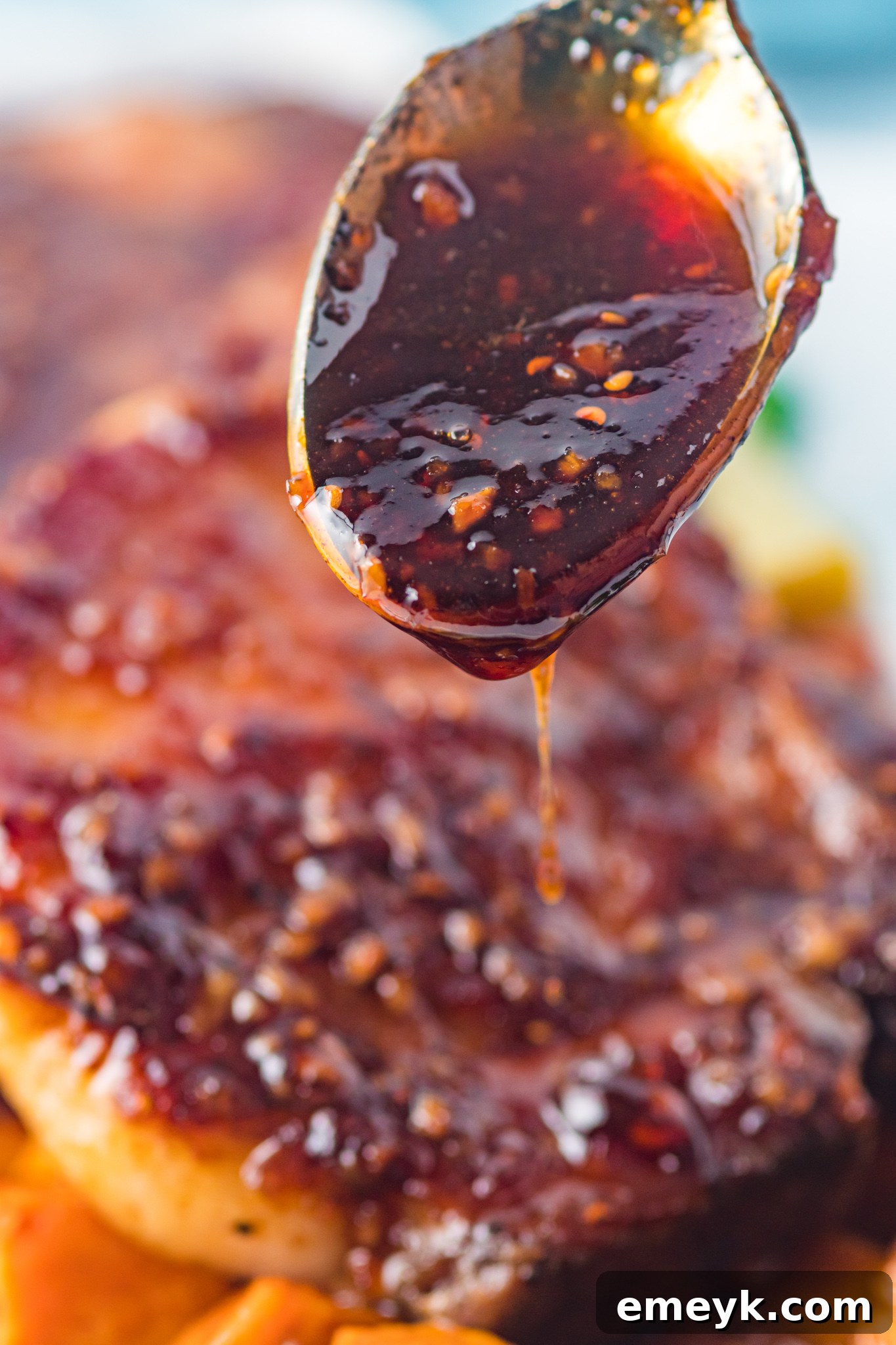 A spoon dripping with rich, sticky Maple Bourbon Glaze, showcasing its luscious texture.