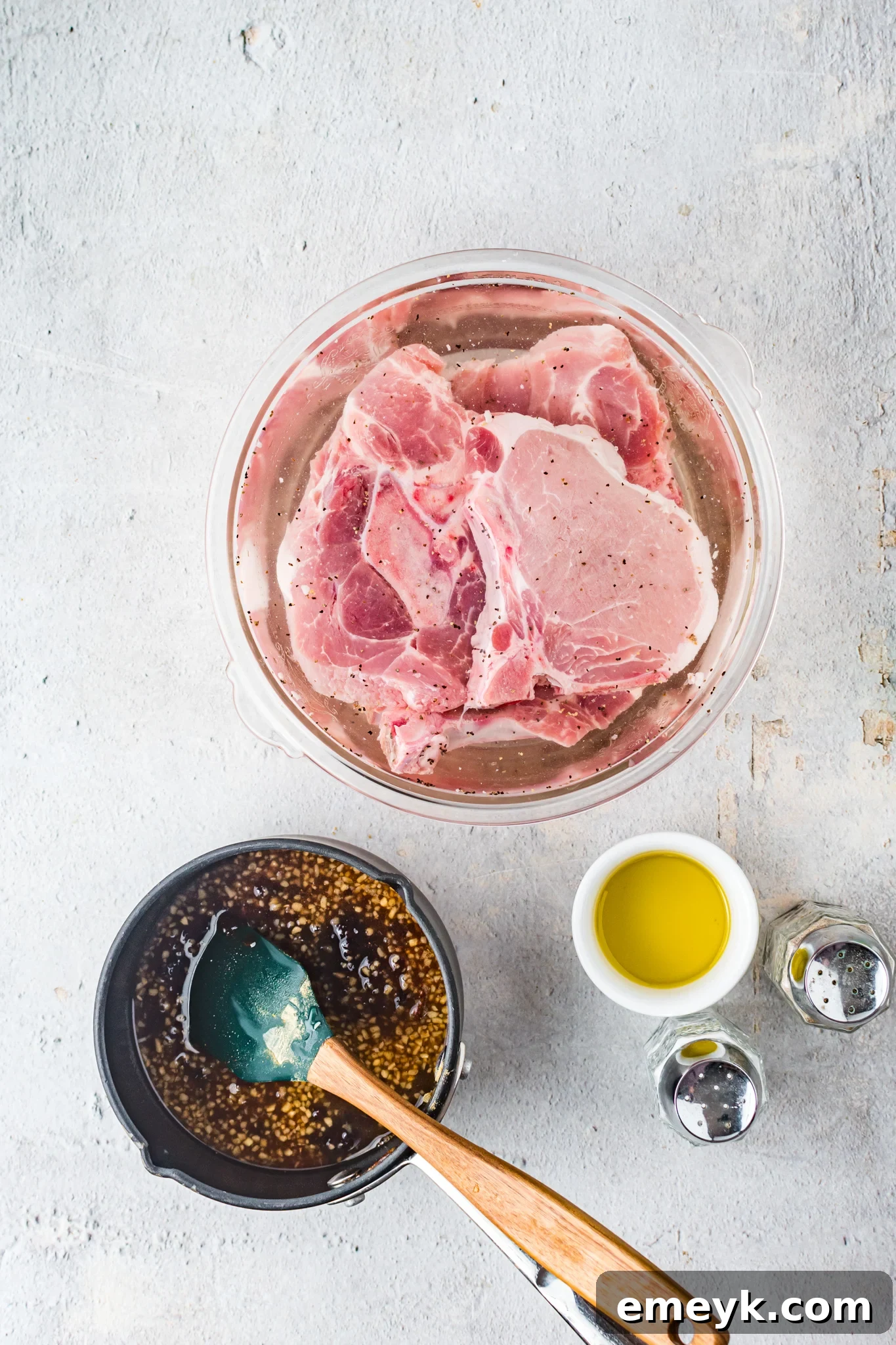 Pork chops soaking in a brining solution in a bowl, preparing for the Maple Bourbon Pork Chops Recipe.