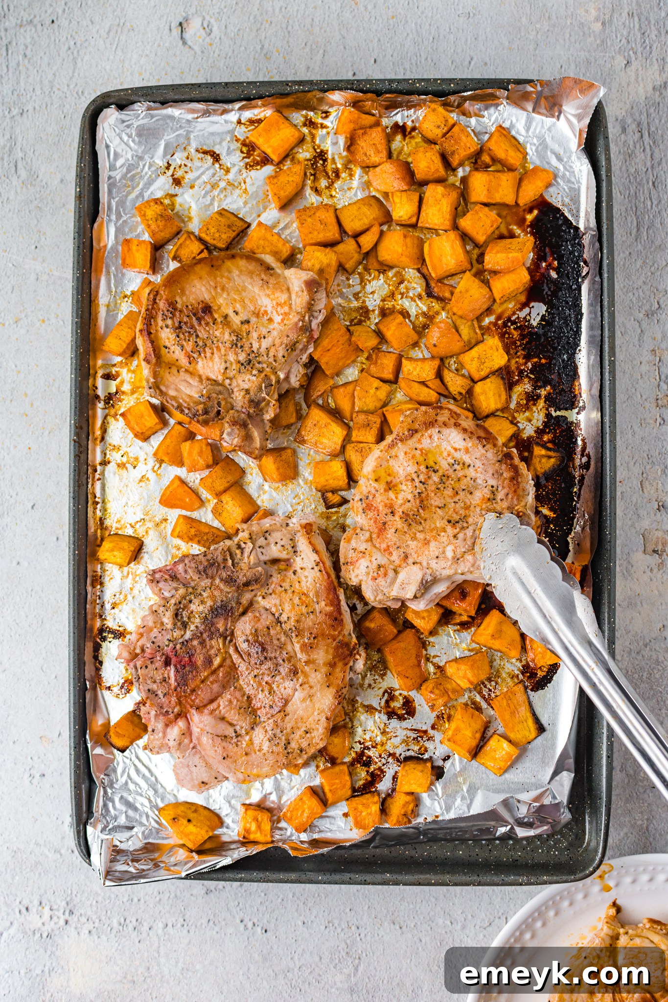 Maple Bourbon Pork Chops being transferred with tongs, showcasing their sticky glaze.